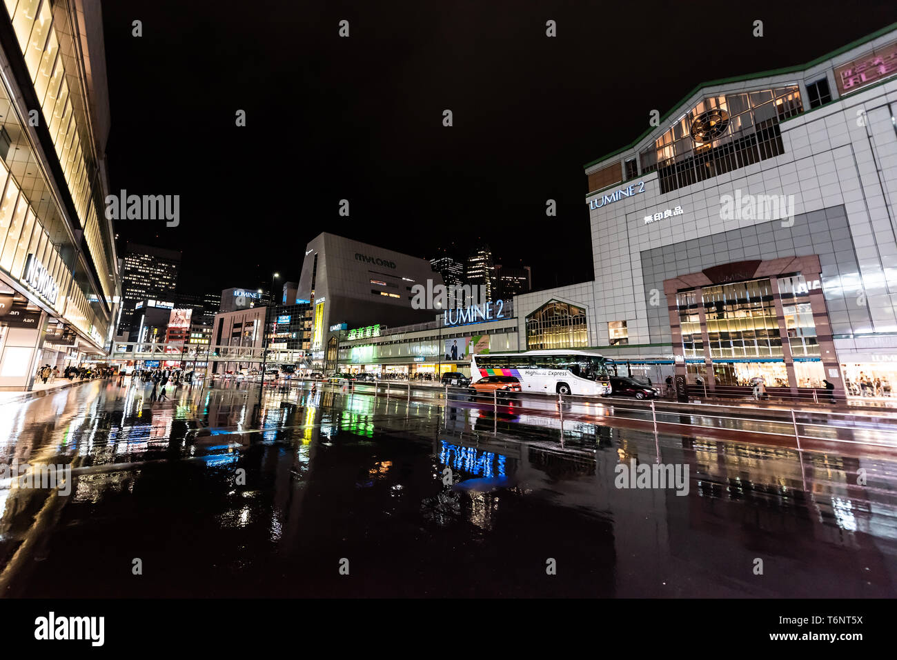 Shinjuku, Japan - 1. April 2019: Großes Einkaufszentrum außerhalb des Bahnhofs in der Innenstadt mit Neon-Lichtern in der Nacht bei Regen mit Re Stockfoto