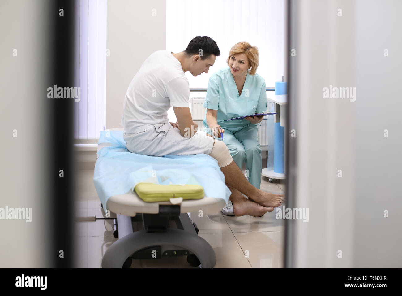 Orthopäde und Patienten mit Bandagierten Bein im Krankenhaus Stockfoto