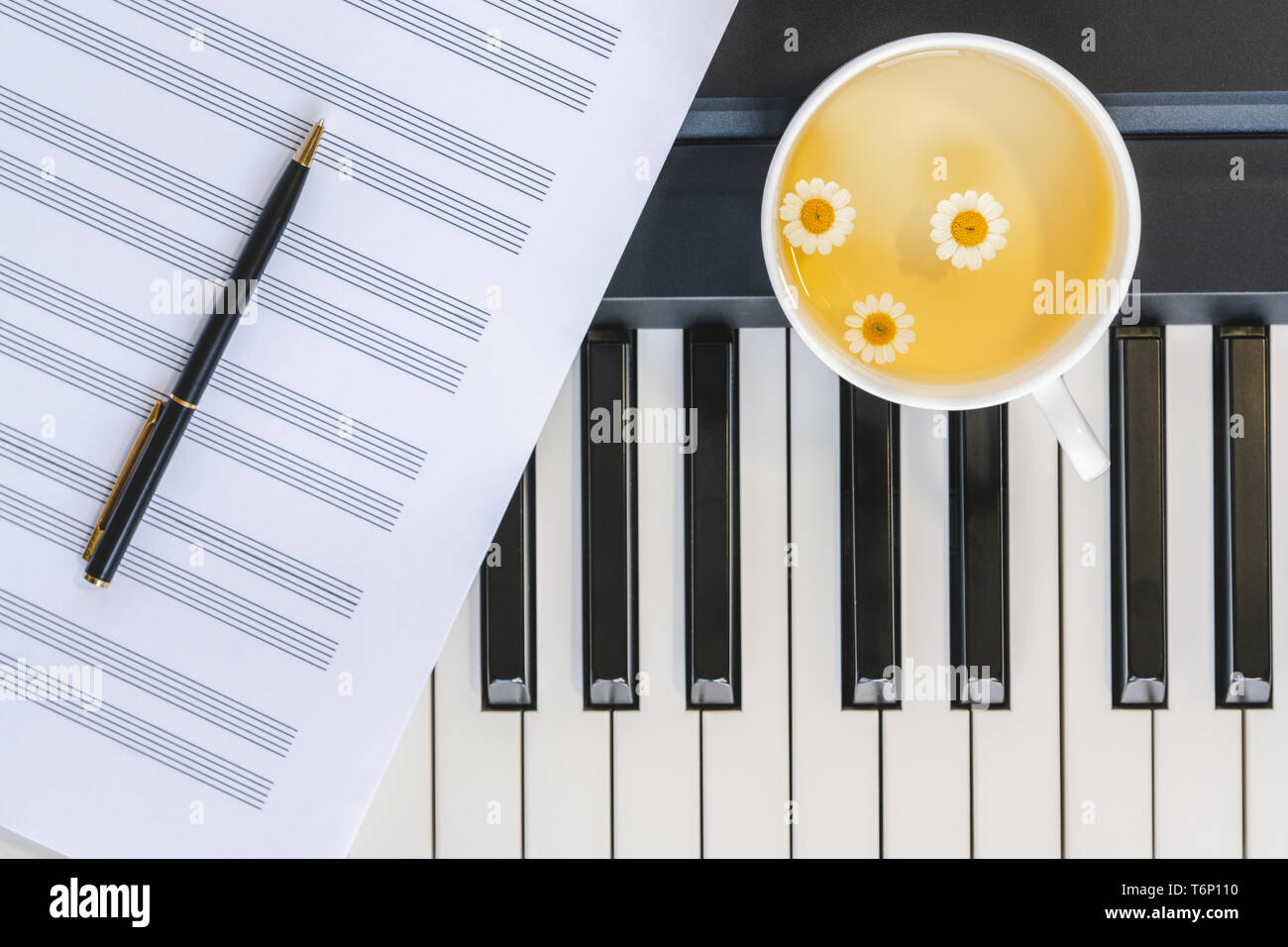 Tasse Kamillentee auf einem Klavier Keyboard, Musik Blatt und Stift. Immer noch leben, Romantik, Konzept Stockfoto
