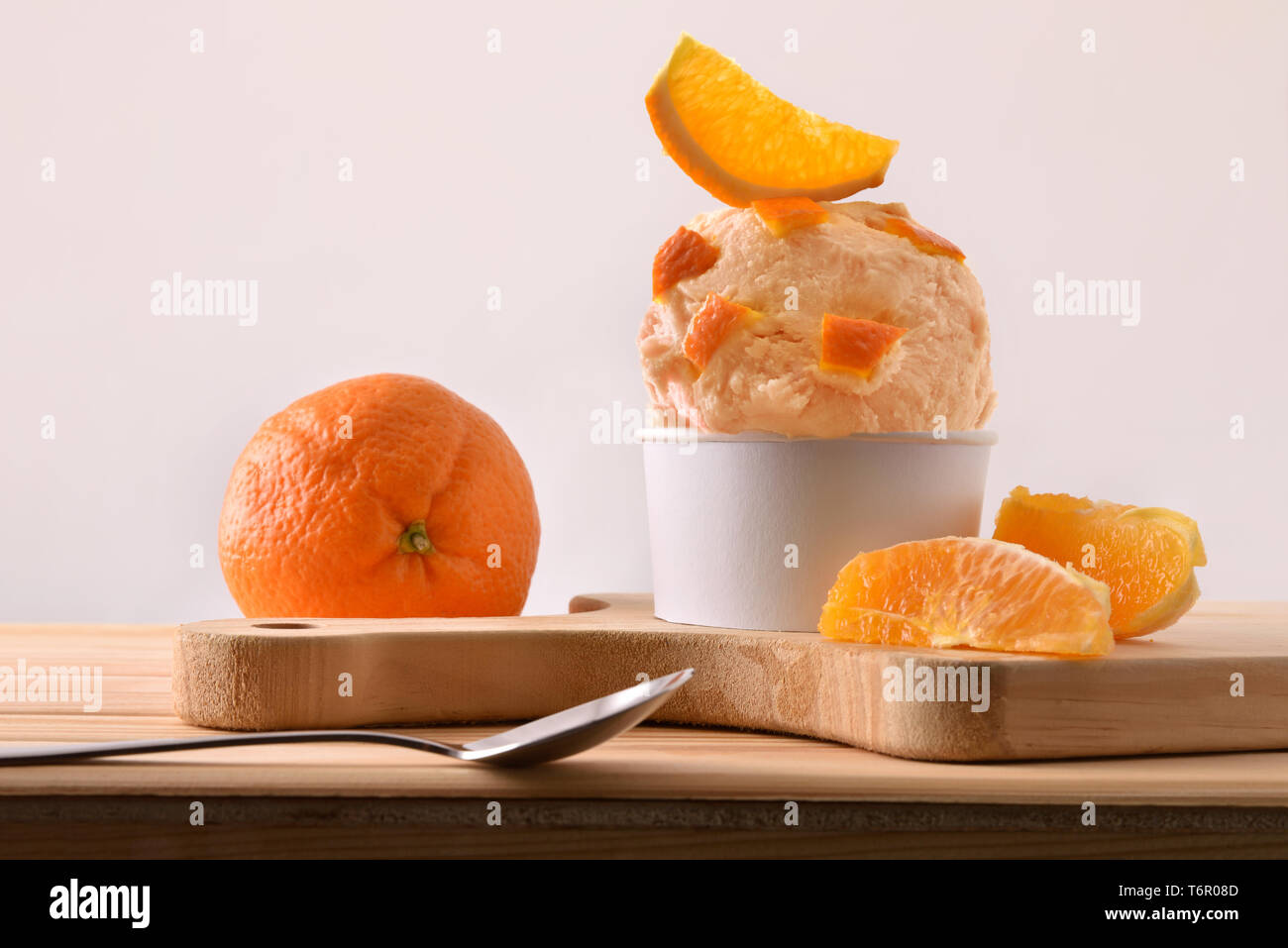 Orange Eisbecher mit orange Segmente auf einem hölzernen Tisch eingerichtet. Horizontale Komposition. Vorderansicht. Stockfoto