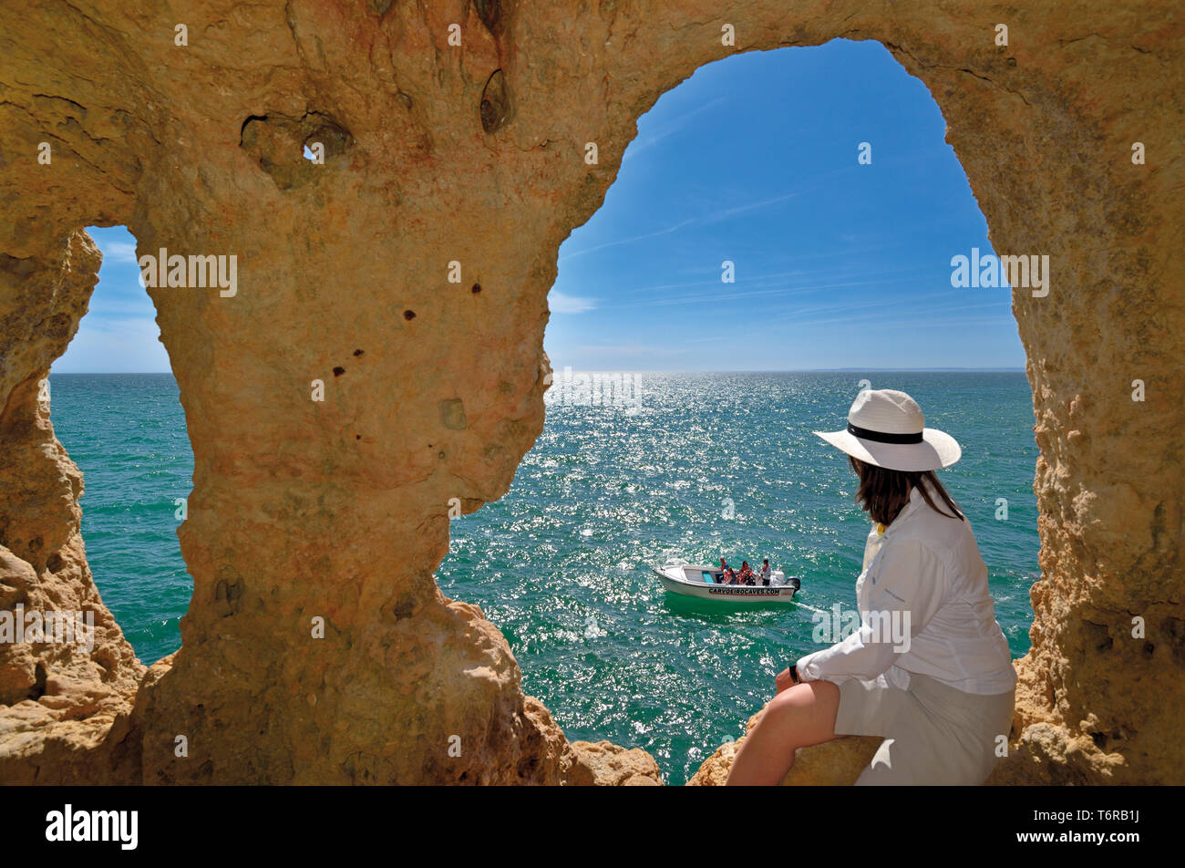 Frau auf der Suche von natürlichen Höhle Fenster zu Green Ocean und touristischen Boot an einem sonnigen Tag Stockfoto