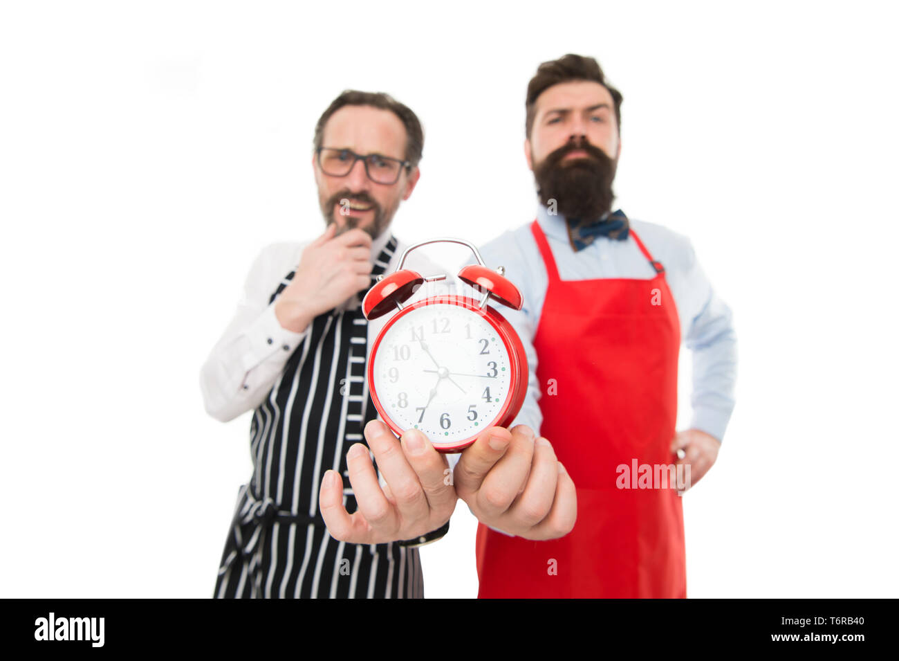 Man bärtige Hipster und reifen Koch Schürze weißen Hintergrund. Arbeitszeit  und Mittagspause. Der Mangel an Zeit. Prüfen welche Zeit ist es. Es ist  Mittagszeit. Männer kocht mit Wecker. Perfekte Disziplin Stockfotografie -