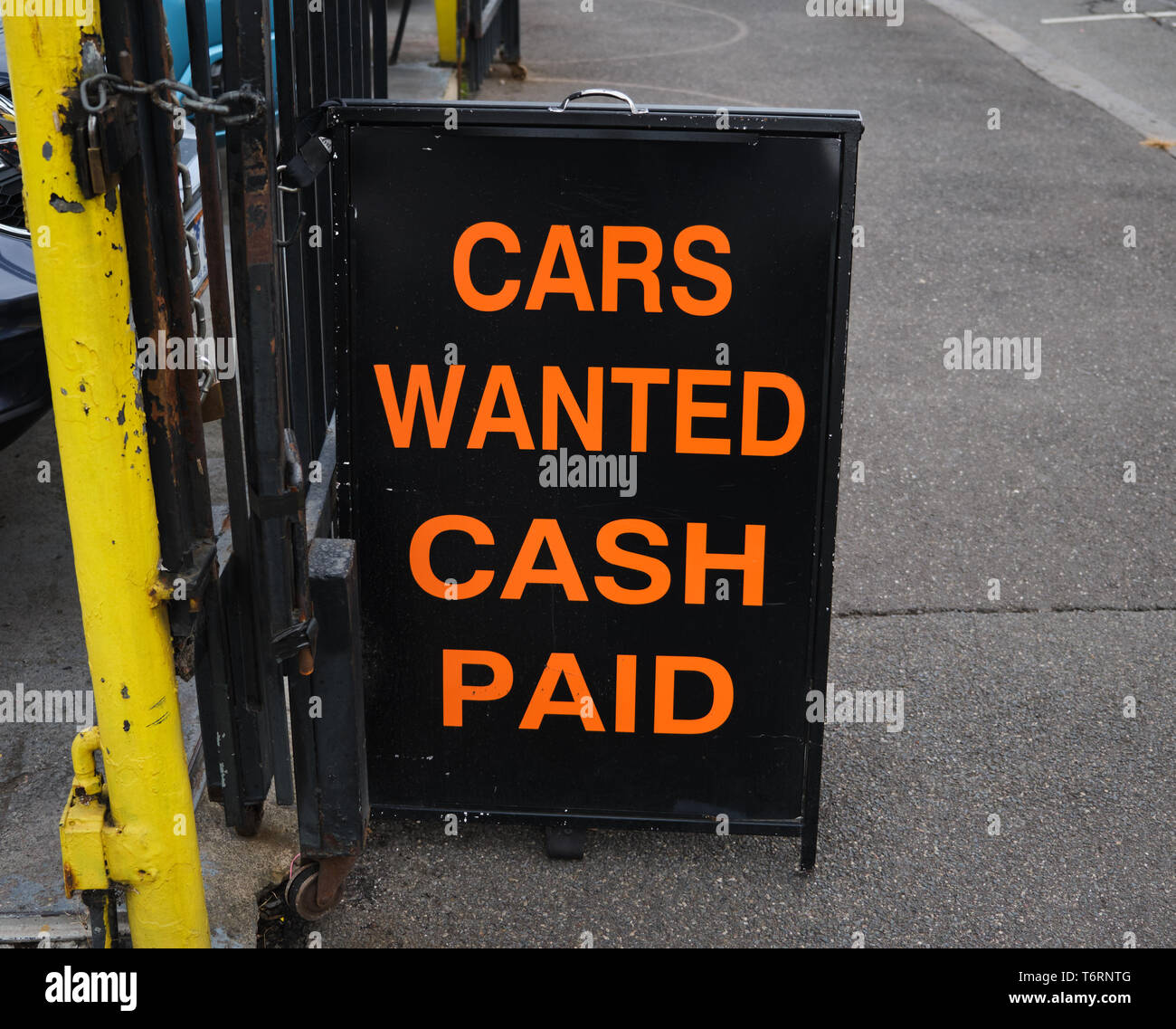 Autos wollte Bar bezahlt Zeichen auf bürgersteig angekettet an Zaun von gebrauchten Autohaus, orange Text auf schwarzem Hintergrund Stockfoto