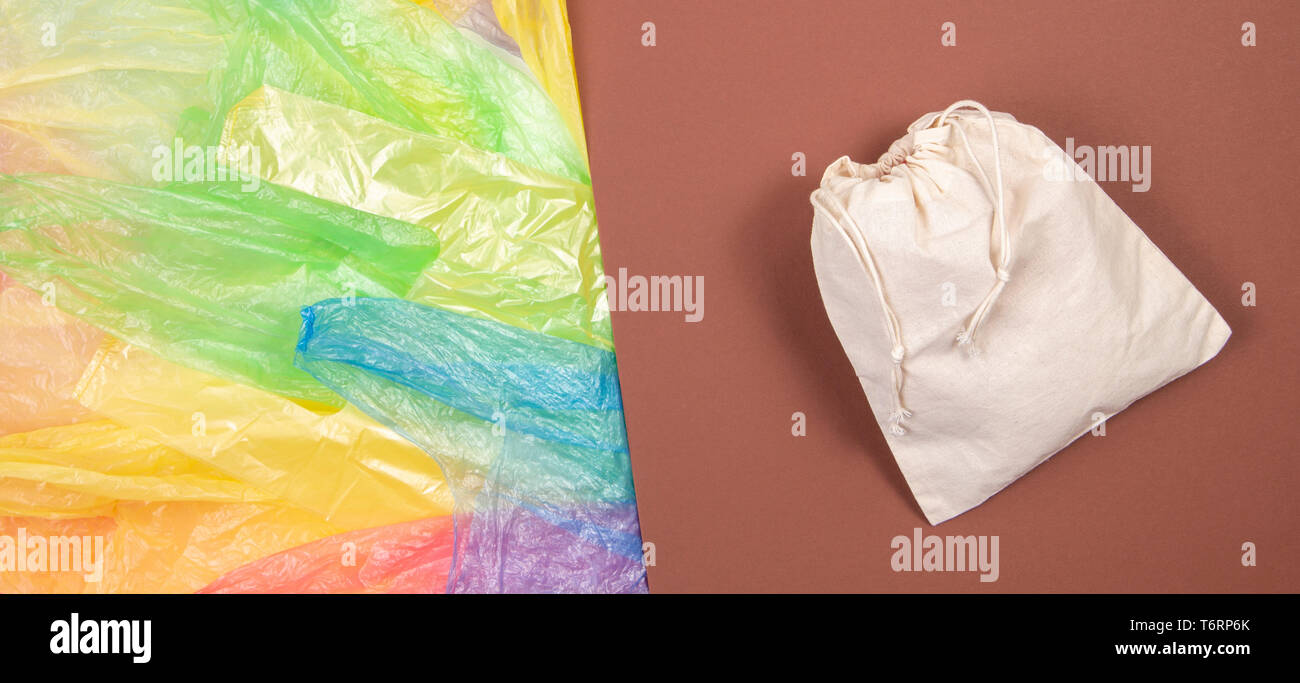 Viele bunte Plastiktüten mit einem eco-natürliche, wiederverwendbare Tasche zum Einkaufen auf braunem Hintergrund. Null Abfall, Umweltfreundlich, kein Plastik Konzept Stockfoto