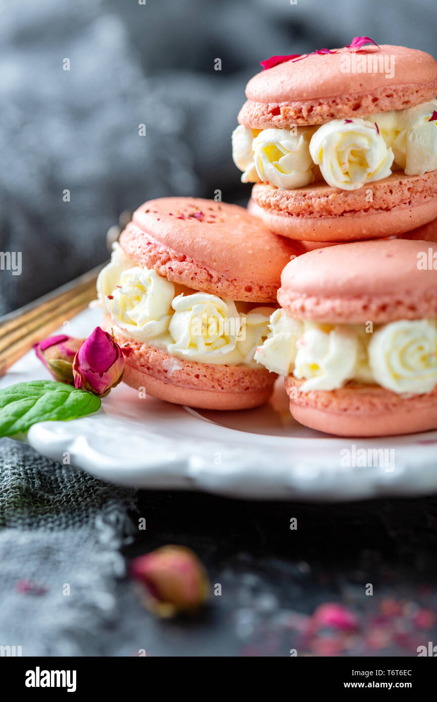 Macarons mit cremefarbenen Rosen. Stockfoto