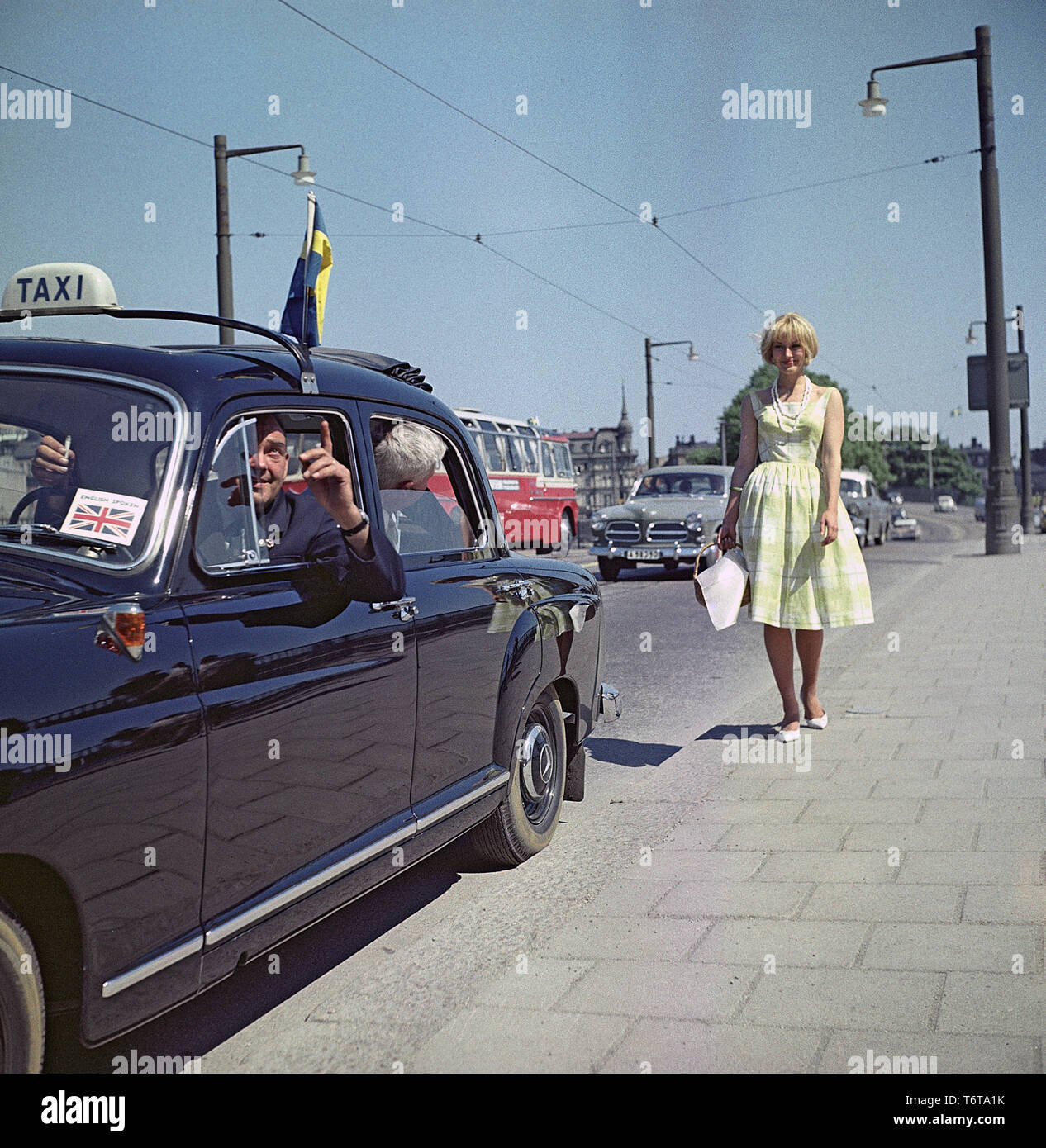 Taxifahrer in den 1960er Jahren. Ein Taxifahrer sieht so aus, als wenn er versucht, etwas Interessantes zu den Touristen auf dem Rücksitz. Er ist jedoch mehr im Blick auf die blonde junge Frau auf dem Bürgersteig interessieren. Schweden 1960 ref BV 71-5 Stockfoto