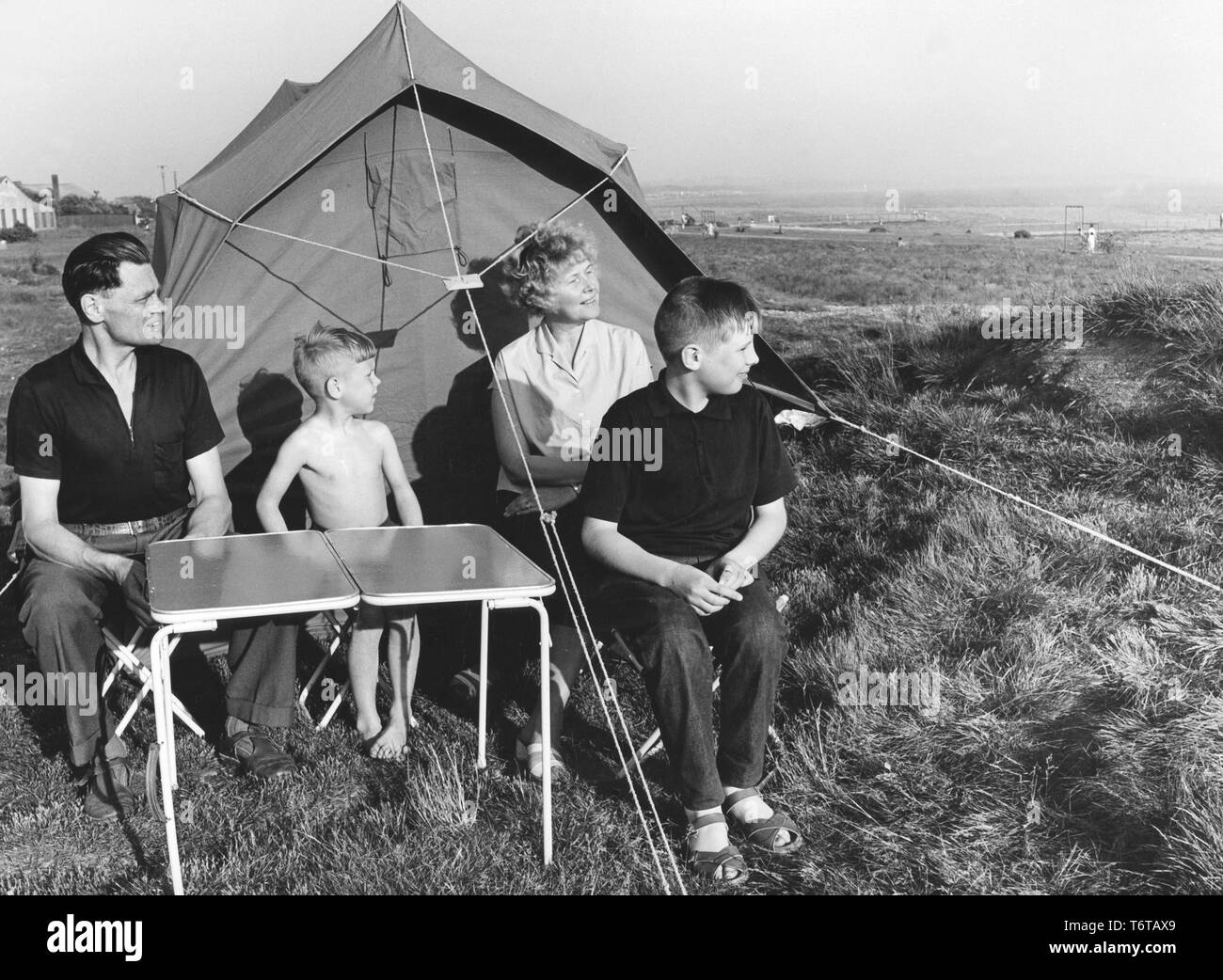 Camping in den 1960er Jahren. Eine Familie außerhalb Ihres Zeltes. Eine einfache und billige Art und Weise Ihren Urlaub zu verbringen. Die wichtigen Klapptisch ist sichtbar, und sie nahm es mit leichter, dass sie weise und nimmt wenig Platz im Kofferraum des Autos. Schweden 1962 Stockfoto