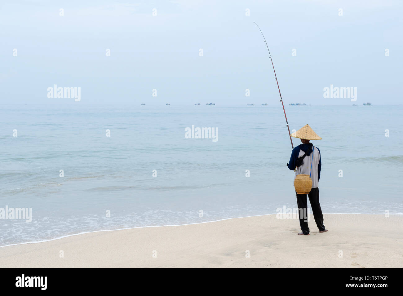 Ein lokaler Mann angeln am Jimbaran Beach auf Bali, Indonesien Stockfoto