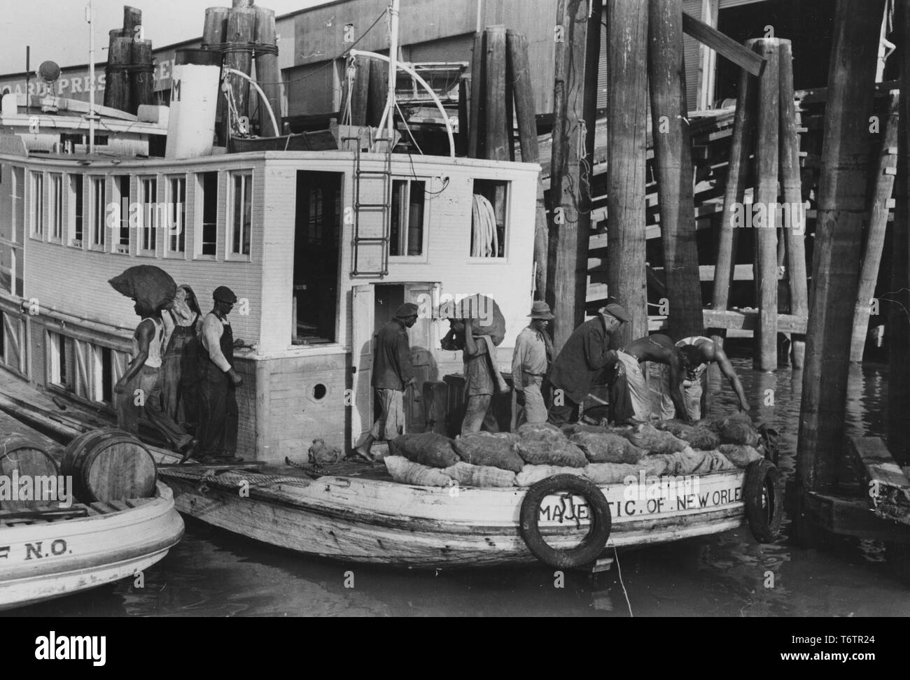 Foto von Afrikanische amerikanische Männer entladen schwere Säcke mit Austern aus ein Paket Boot Dock, New Orleans, Louisiana, 1935. Von der New York Public Library. () Stockfoto