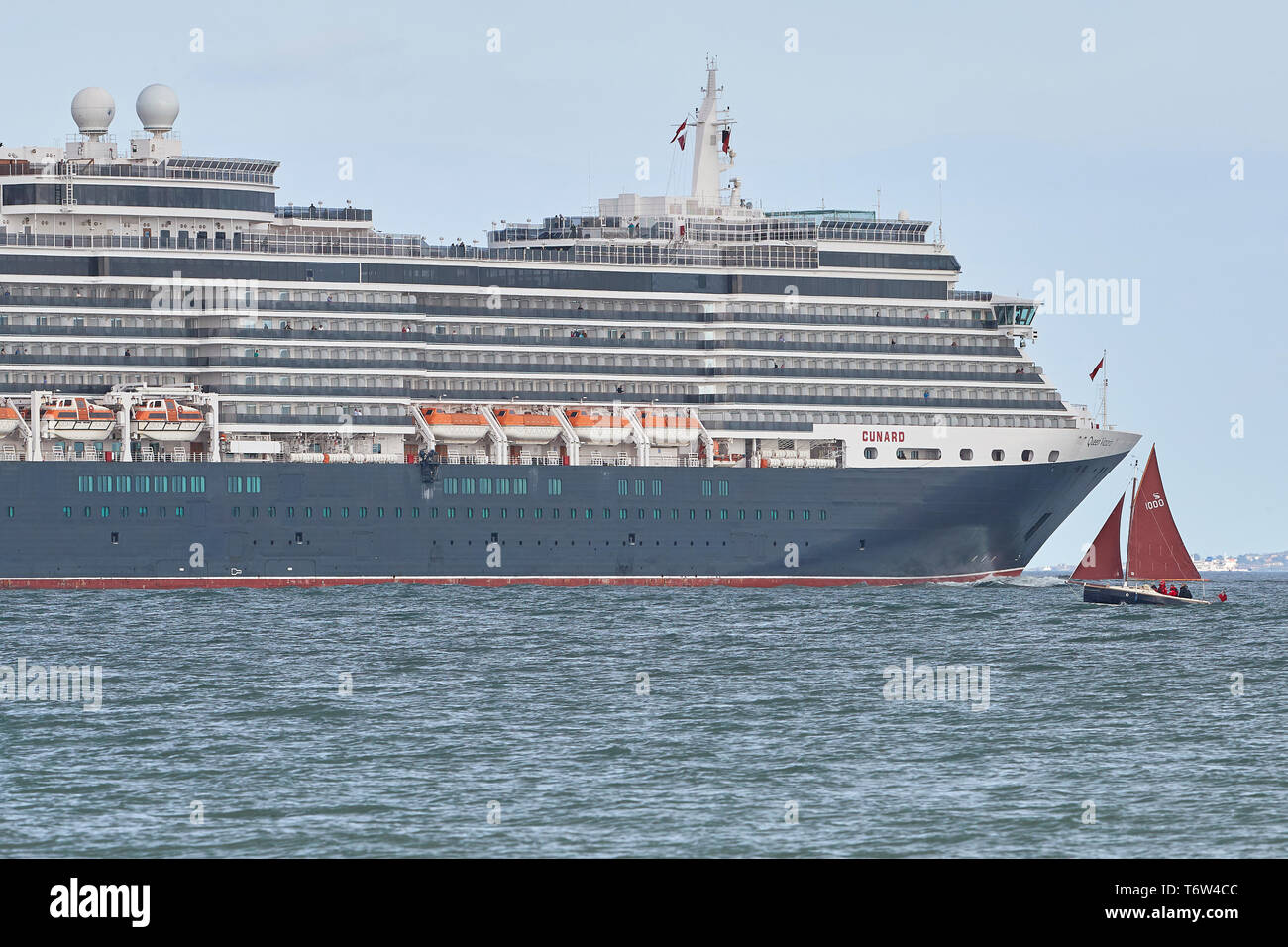 Die riesigen, Cunard Line, MS QUEEN VICTORIA, Nahe einem kleinen Segelboot, wie Sie Segel aus Southampton, UK, für Hamburg. 28. April 2019. Stockfoto