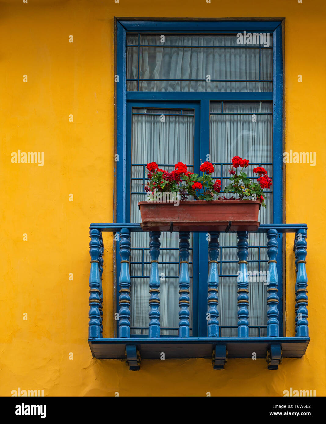 Balkon mit blauen Fensterrahmen und gelbe Wand in der historischen Altstadt von Cuenca, Ecuador. Stockfoto