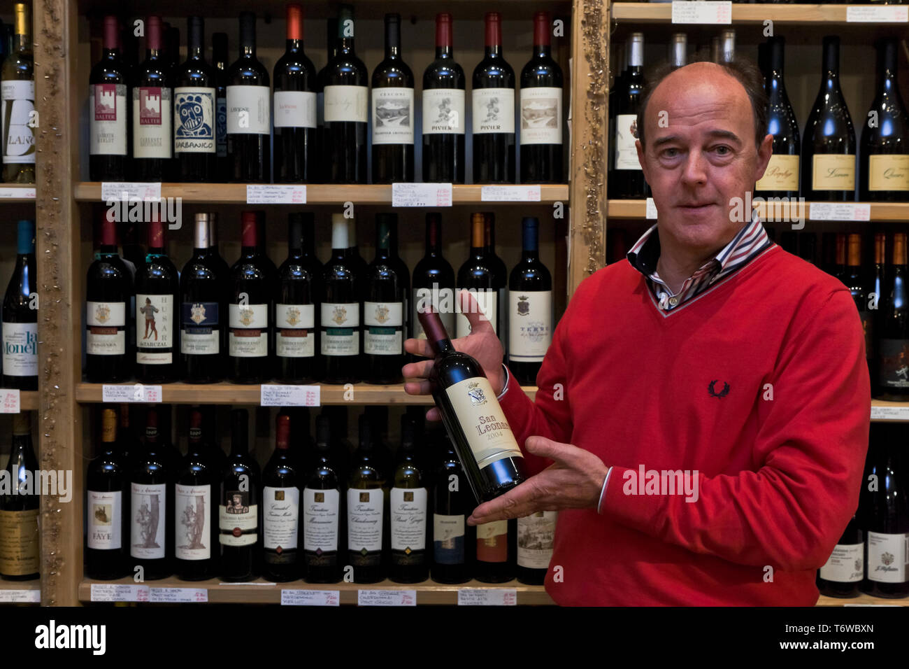 Rovereto, drogheria Giuseppe Micheli: Gli scaffali con le bottiglie di Vini tipici del Trentino. Il proprietario Mostra una bottiglia di San Leonardo. Stockfoto