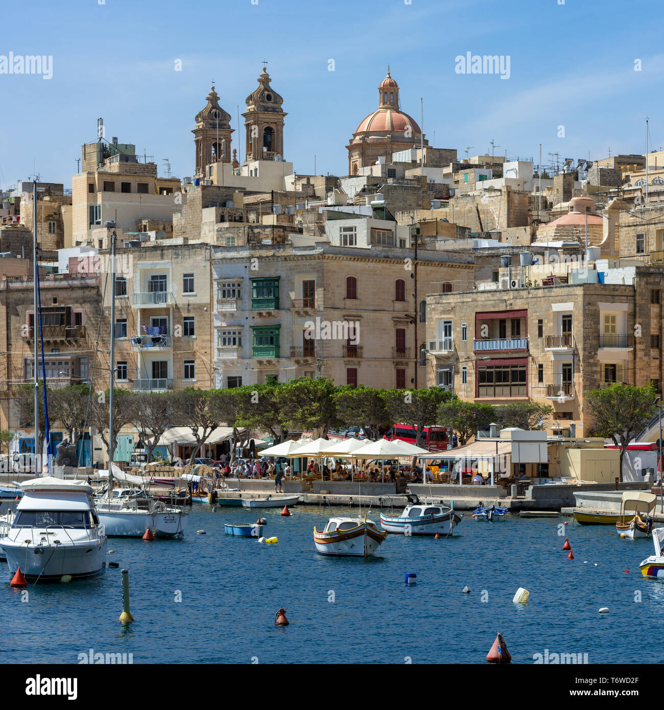 Die baumgesäumte Uferpromenade von Senglea in Malta mit ihren historischen Kalksteingebäuden, die zu den zwei Glockentürmen und der Kuppel der Senglea-Basilika führen Stockfoto