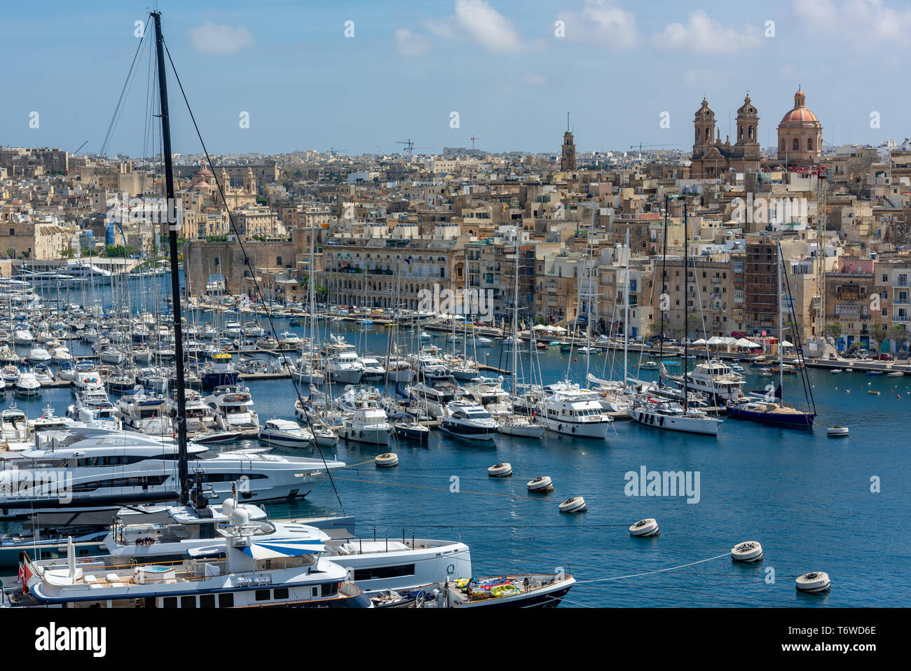 Luxusyachten und Vergnügungsboote, die in Dockyard Creek im Grand Harbour von Valletta festgemacht sind, blicken auf die Basilika der Geburt Mariens, Senglea Stockfoto