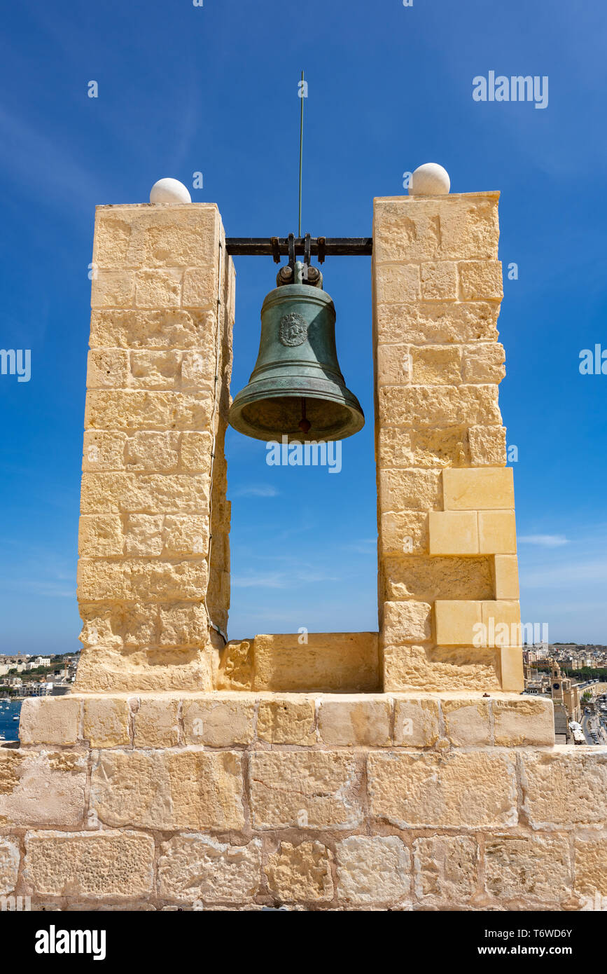 Eine große Bronzeglocke, die zwischen zwei Kalksteinsäulen in Fort St Angelo auf der Birgu-Halbinsel auf Malta schwebt Stockfoto