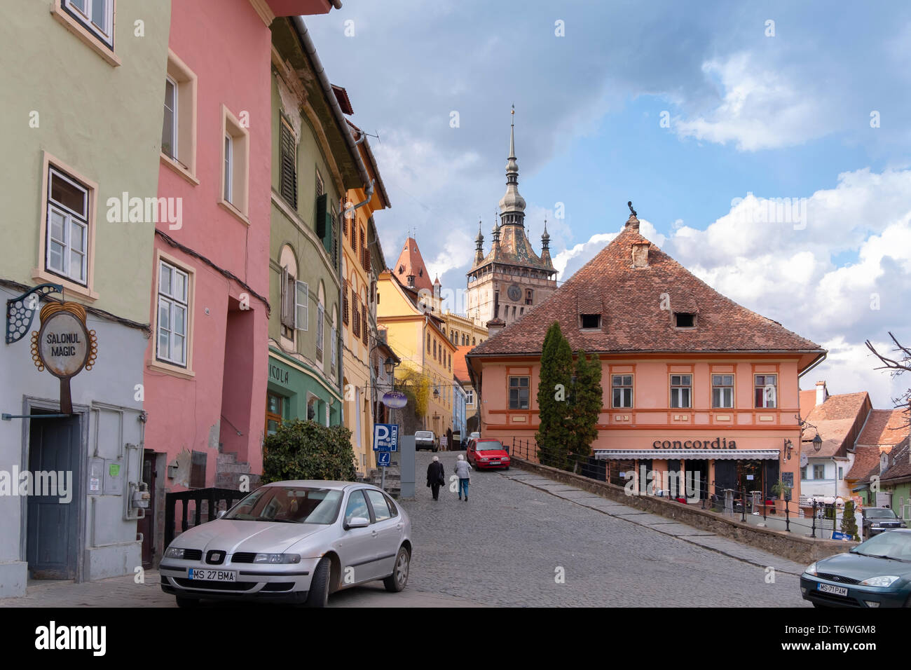 SIGHISOARA, Rumänien - April 9, 2019: Bunte Dächer und Häuser im Zentrum von Sighisoara. Street Scene an einem sonnigen Tag mit älteren Menschen zu Fuß Stockfoto