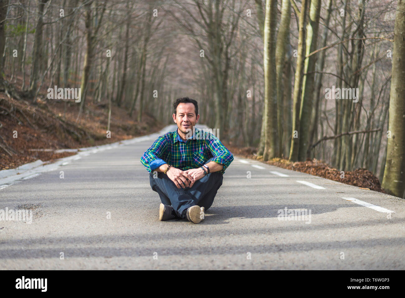 Vorderansicht eines Mannes auf der Suche Kamera, sitzen auf den ländlichen Straße im Herbst Stockfoto