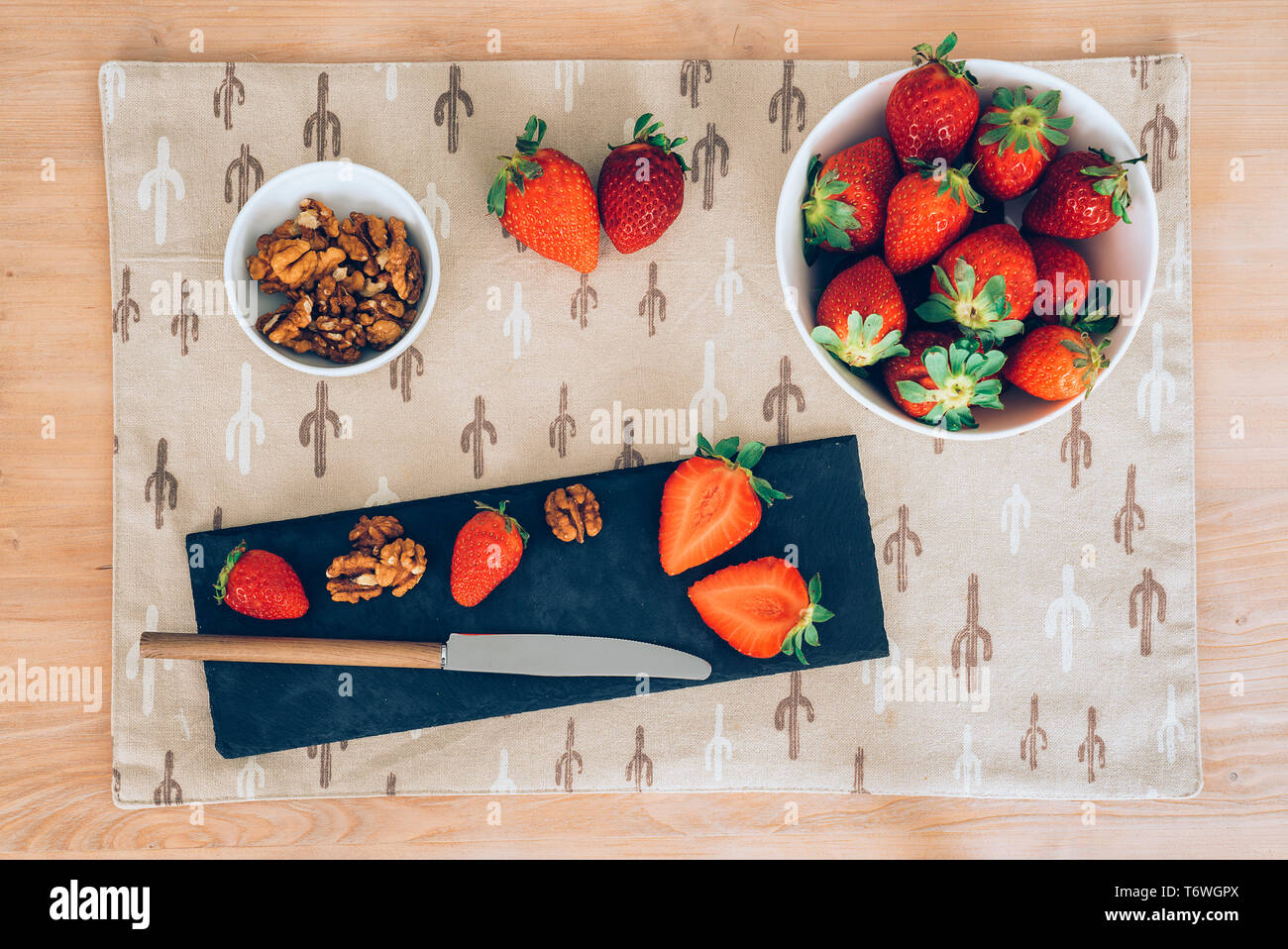 Blick von oben auf eine saftige frische Erdbeeren und Muttern mit einem Messer, der mit einem weißen Hintergrund. Gesundes Frühstück oder Dessert. Stockfoto