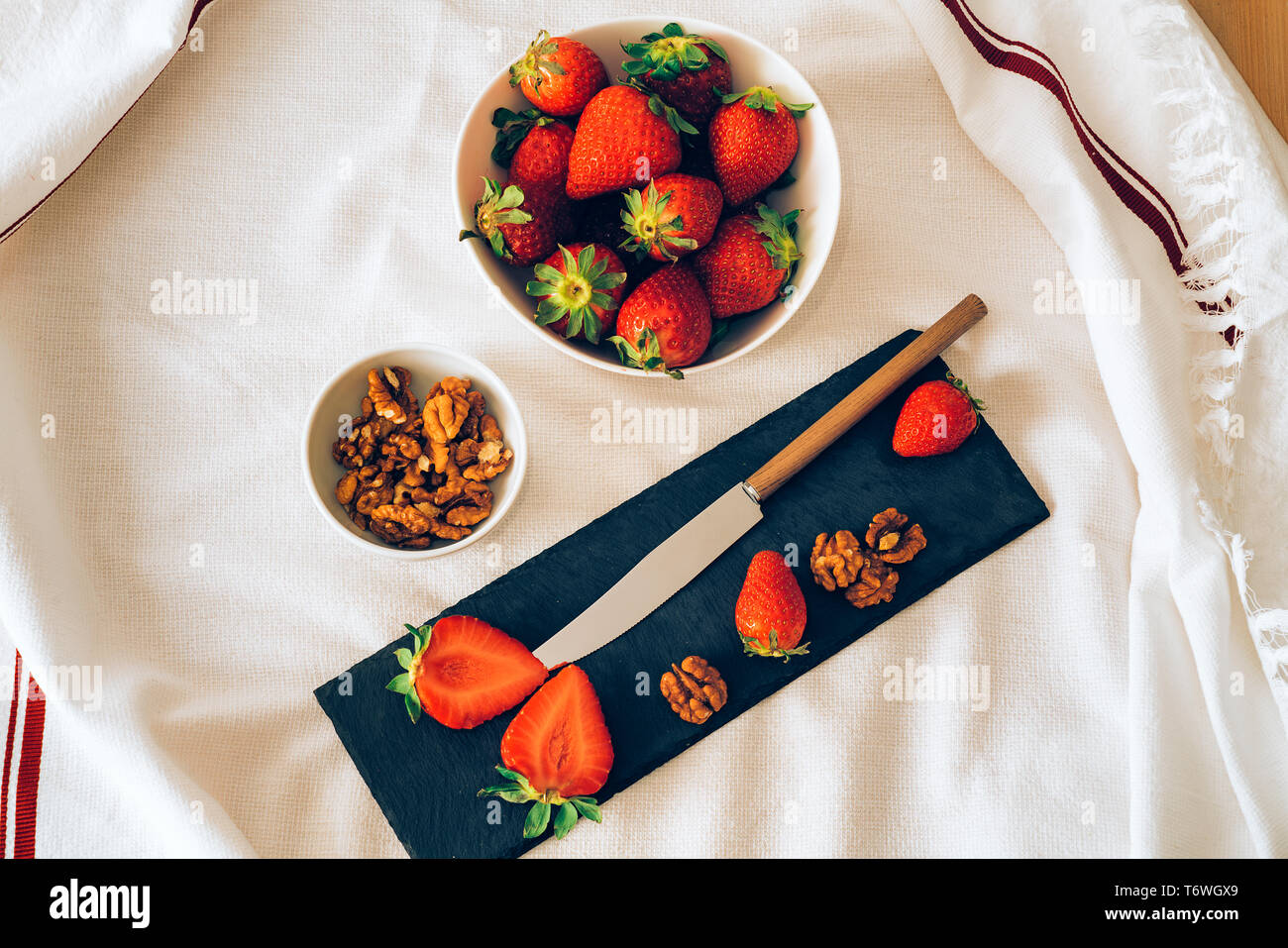 Blick von oben auf eine saftige frische Erdbeeren und Muttern mit einem Messer, der mit einem weißen Hintergrund. Gesundes Frühstück oder Dessert. Stockfoto