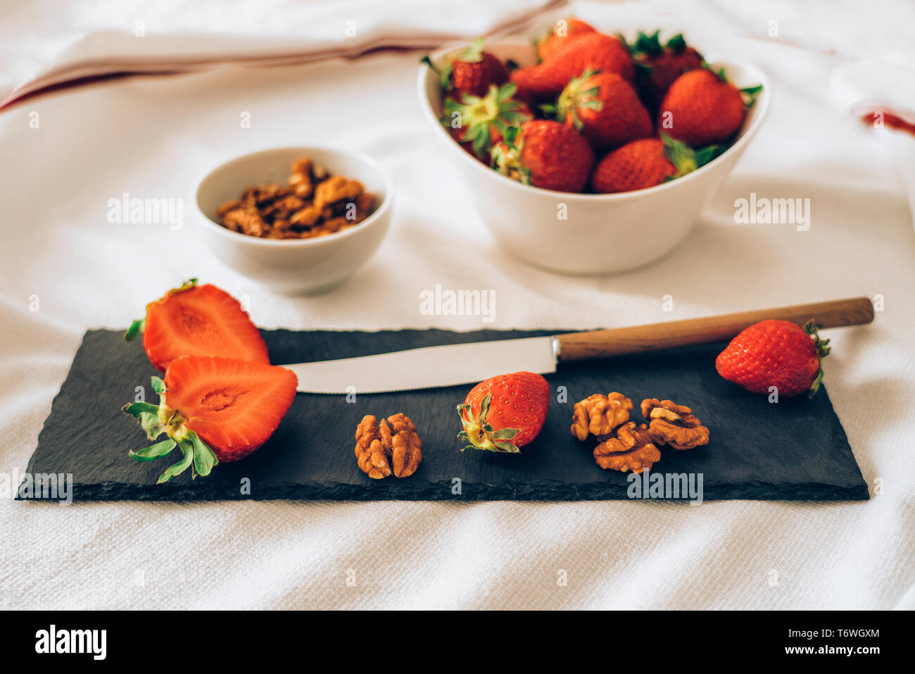 Detailansicht einer saftigen frische Erdbeeren und Muttern mit einem Messer, der mit einem weißen Hintergrund. Gesundes Frühstück oder Dessert. Stockfoto