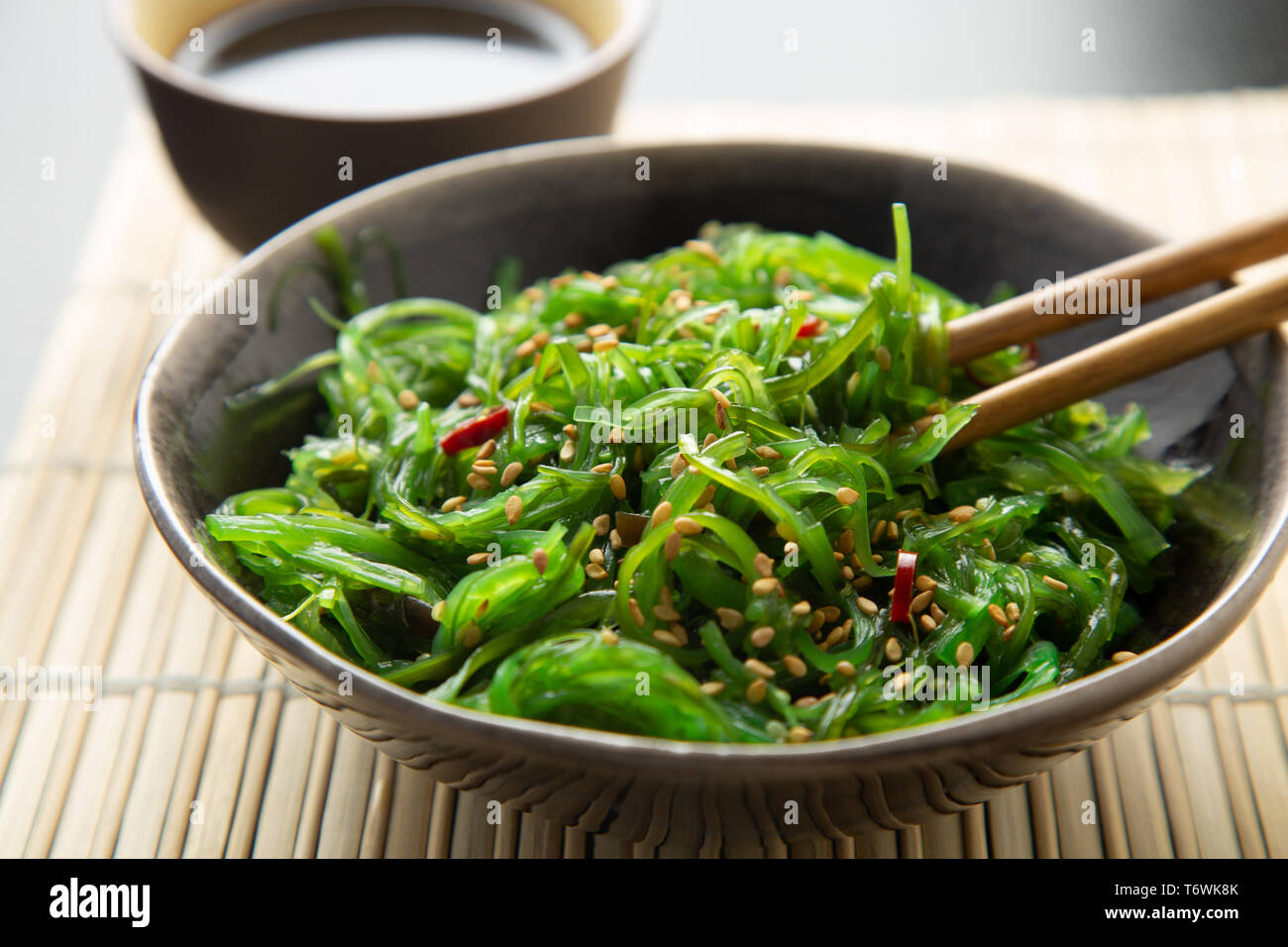 Wakame Algen Salat mit Sesam und Chili Pfeffer in einer Schssel auf einem  Bambus Matte Stockfotografie - Alamy