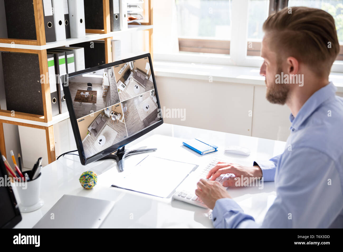 Ansicht der Rückseite des Security System Operators an CCTV-Aufnahmen am Schreibtisch im Büro suchen Stockfoto