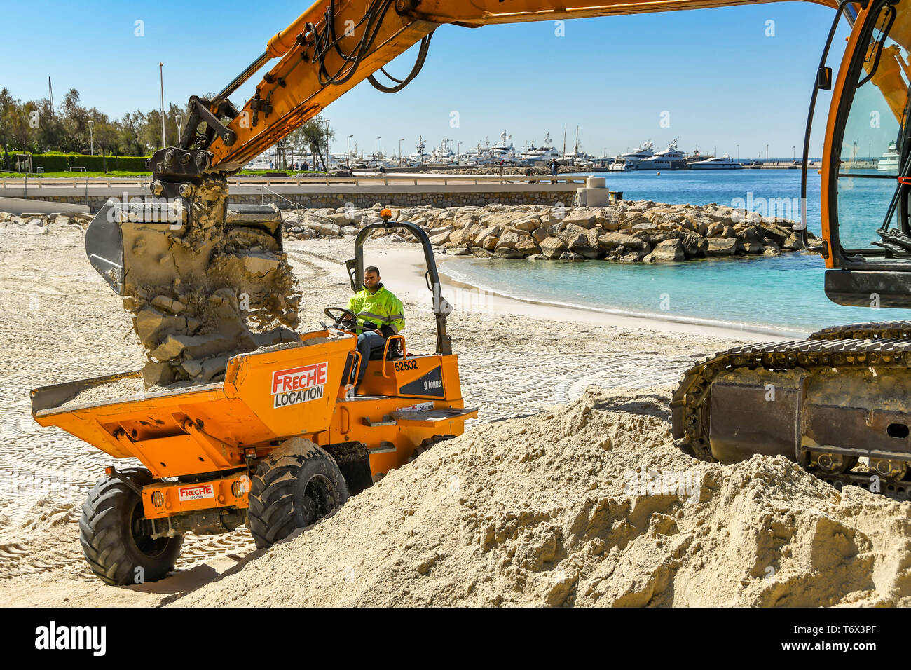 CANNES, Frankreich - April 2019: Der Schaufel von einem Bagger drop Sand in einen Kipper den Strand zu verbessern in Cannes für die Ferienzeit bereit Stockfoto