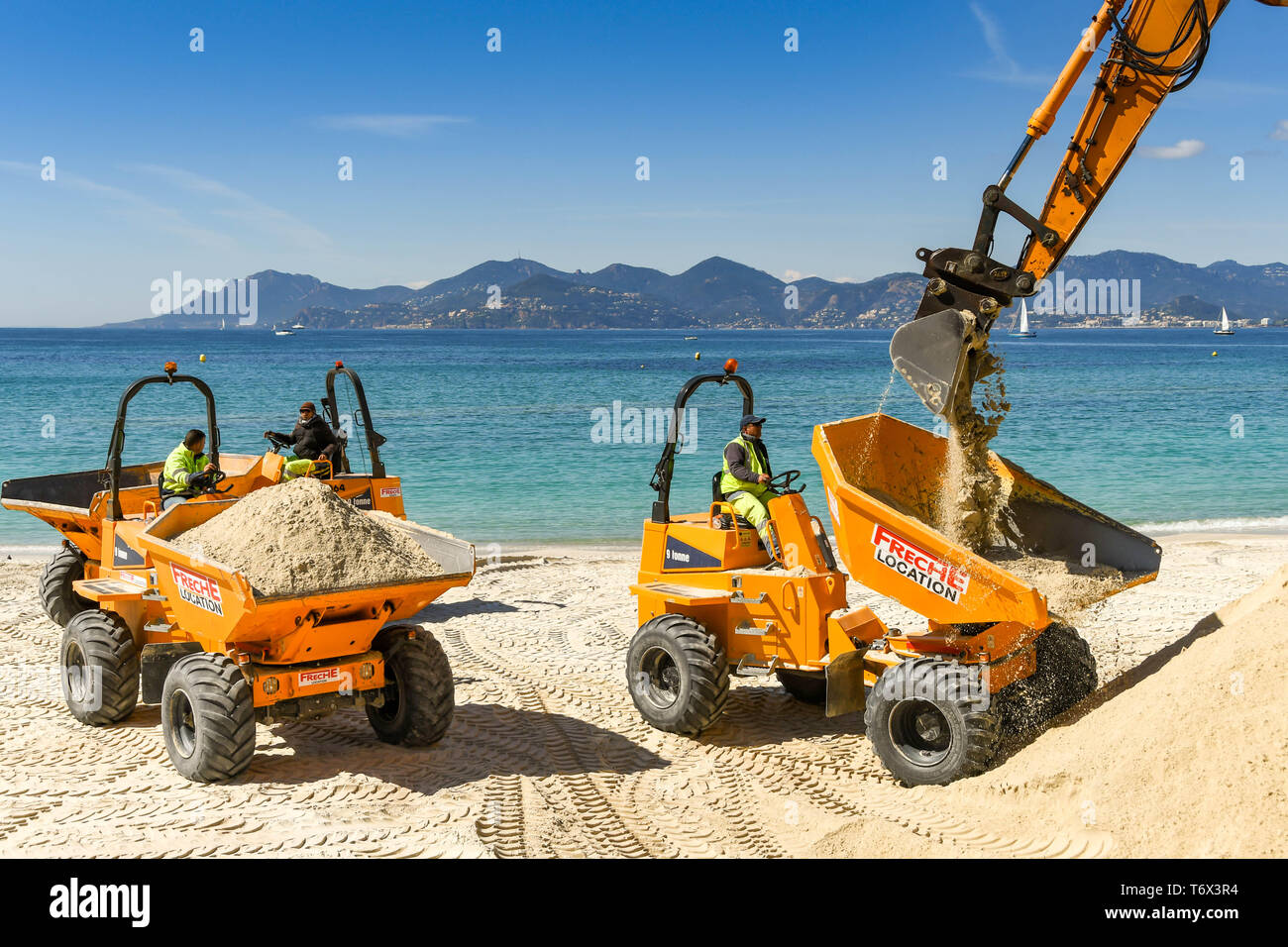 CANNES, Frankreich - April 2019: Der Schaufel von einem Bagger drop Sand in einen Kipper den Strand zu verbessern in Cannes für die Ferienzeit bereit Stockfoto