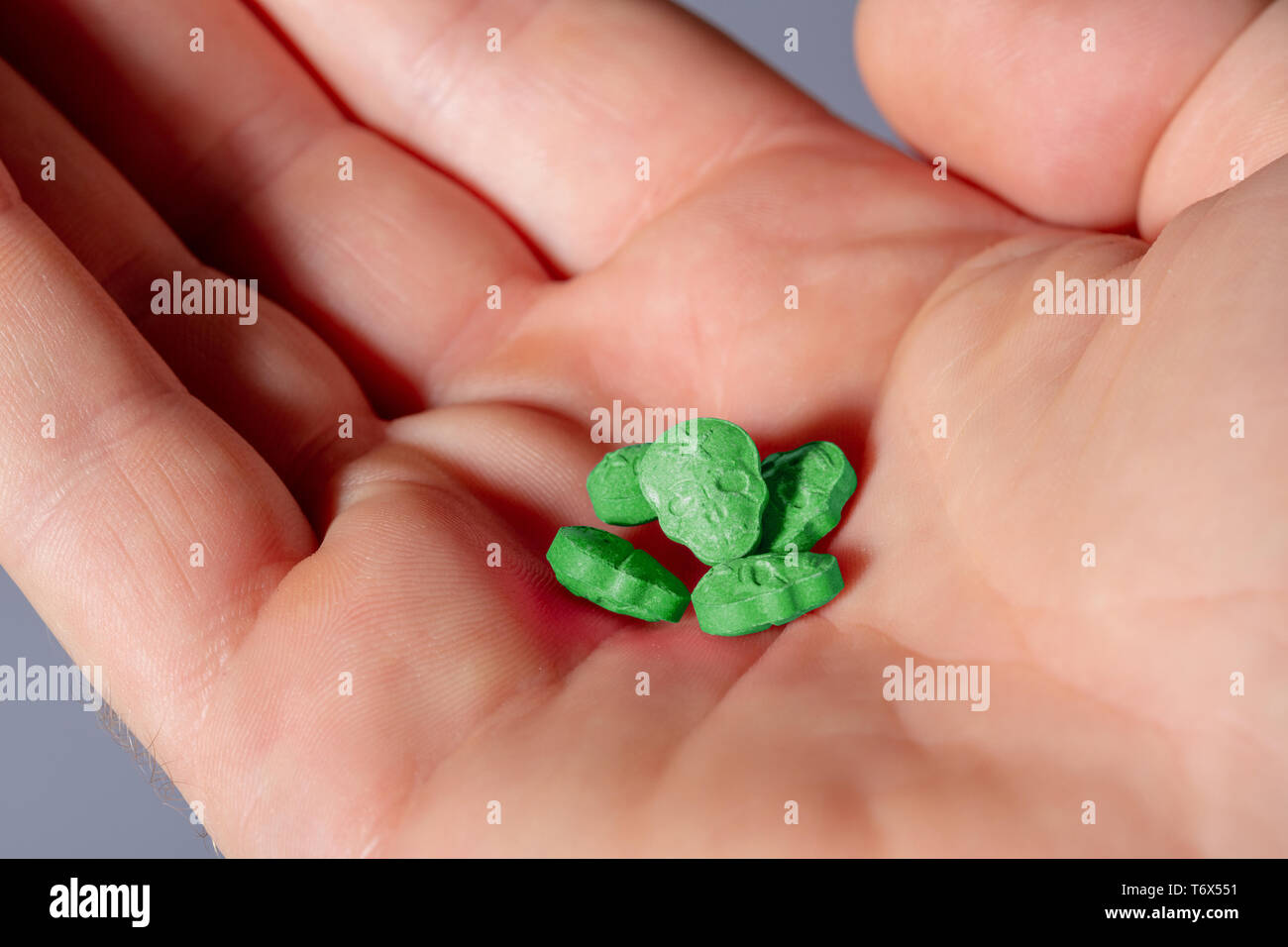 Eine offene Europäische männlich Hand mit einem kleinen Haufen grüne Armee Schädel, Ecstasy, MDMA, Amphetaminen oder Medikamente wie ein Schädel geprägt. Stockfoto