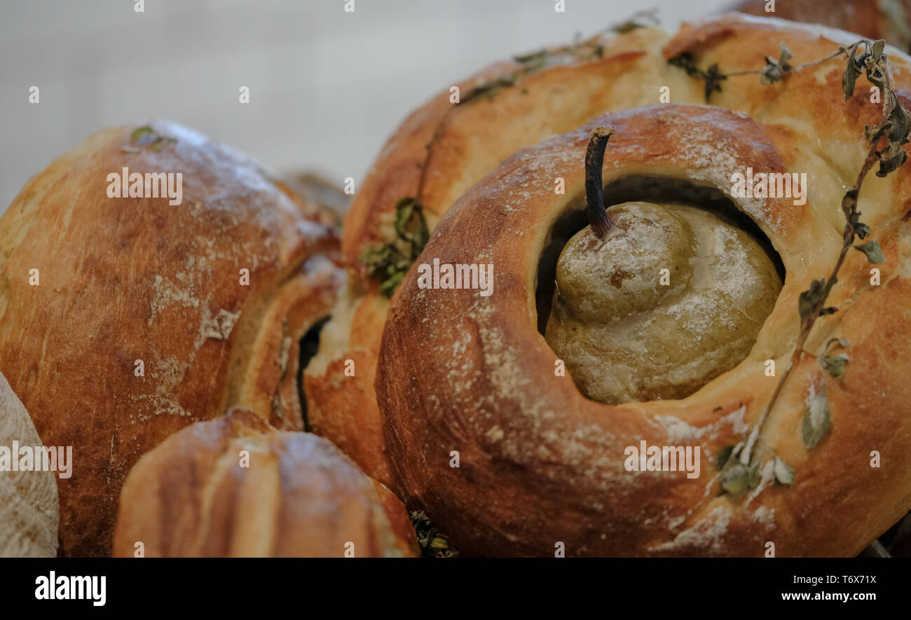 Runde Laib Sauerteig Brot, gebacken mit einer Birne in der Mitte und frischen Kräutern auf bestreut. Stockfoto