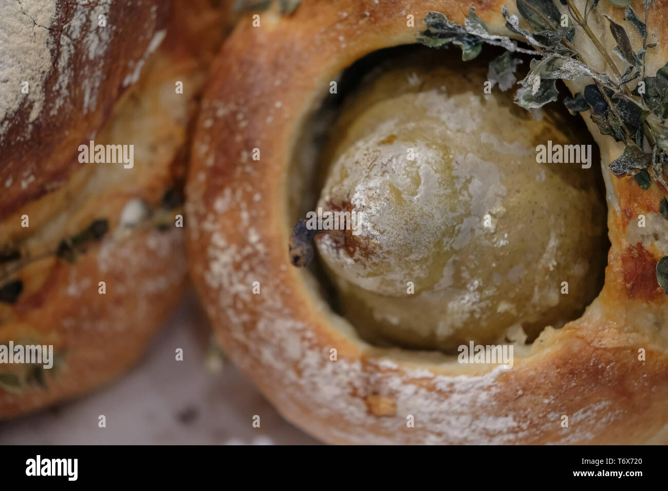 Runde Laib Sauerteig Brot, gebacken mit einer Birne in der Mitte und frischen Kräutern auf bestreut. Stockfoto