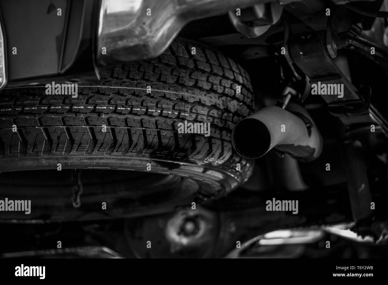 Reserverad unter dem Fahrzeug in der Nähe der Auspuffleitung. Reserverad. Gummi Produkt. Auto Check-up vor dem Travel Concept. Lkw-Ersatzreifen. Konzept Stockfoto