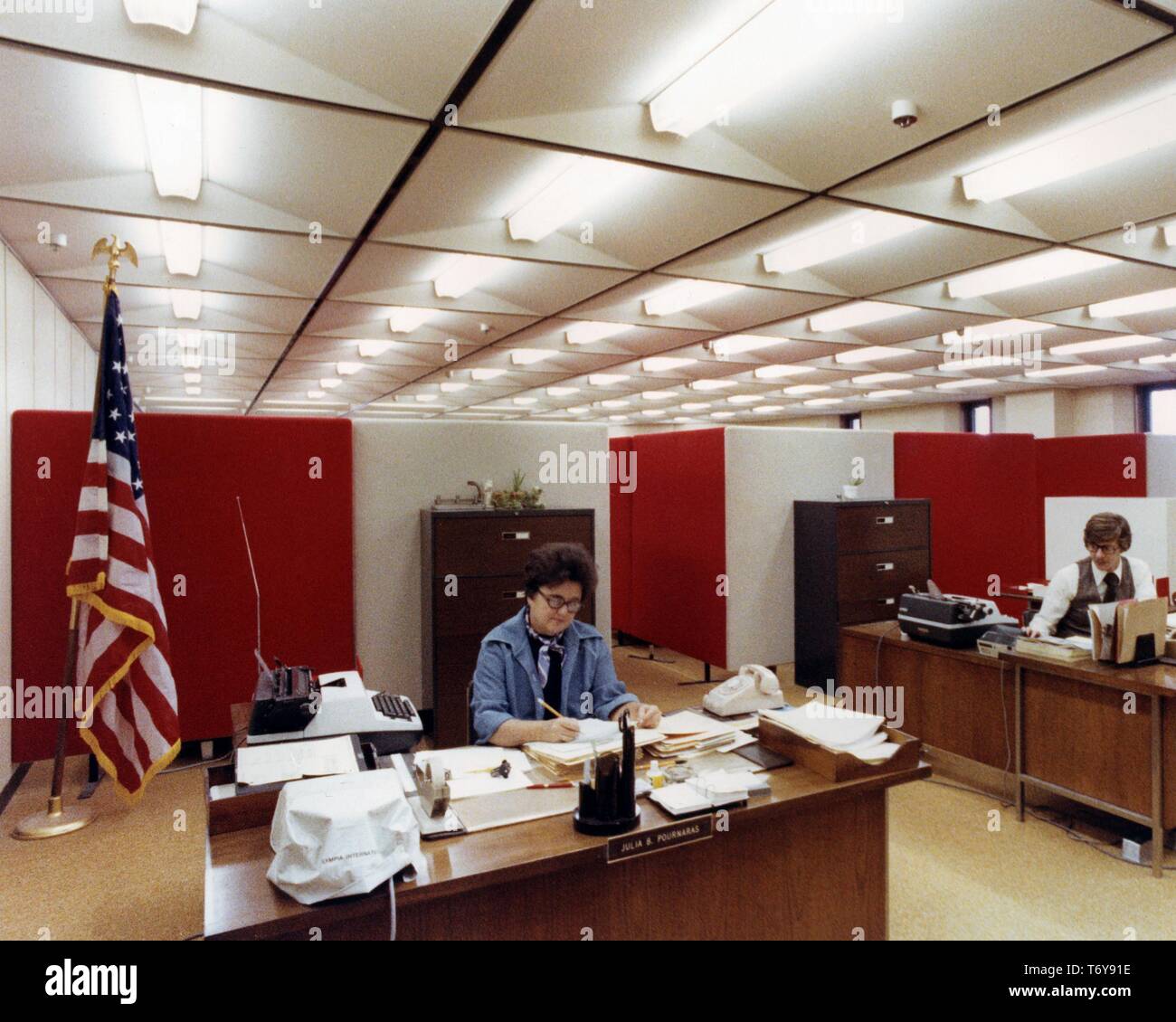 Mitarbeiter, einschließlich Julia B Pournaras, arbeiten an ihren Schreibtischen unter Energieeffiziente Beleuchtung über Halogen-Schienen an der Norris Baumwolle Federal Building, Manchester, New Hampshire, 1975. Mit freundlicher Genehmigung des US-Ministeriums für Energie. () Stockfoto