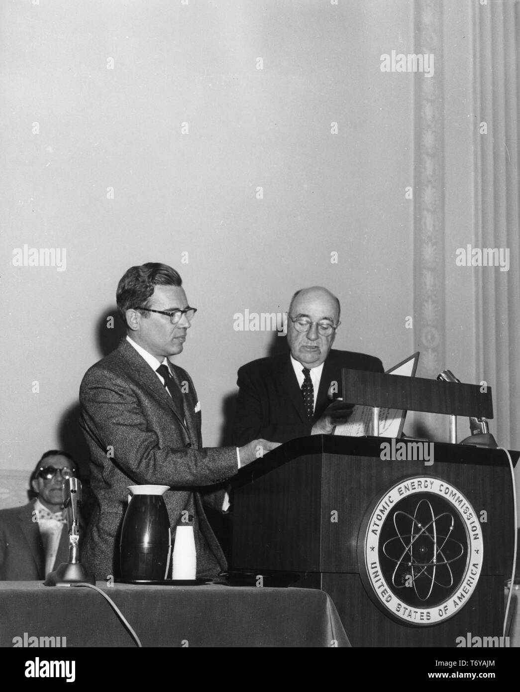 Physiker Henry Hurwitz Jr (links) steht neben einem Podium, während das Ernest Orlando Lawrence Award, mit Leo Brauer im Hintergrund sitzt, Washington DC, Juli, 1961. Mit freundlicher Genehmigung des US-Ministeriums für Energie. () Stockfoto