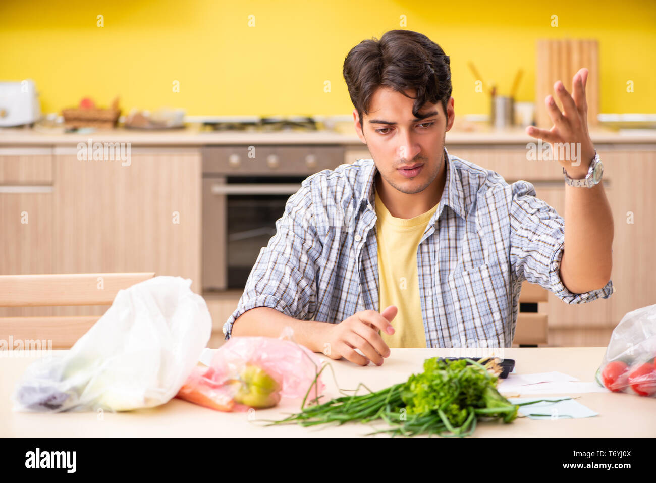 Junger Mann, der Berechnung der Kosten für Gemüse in der Küche Stockfoto