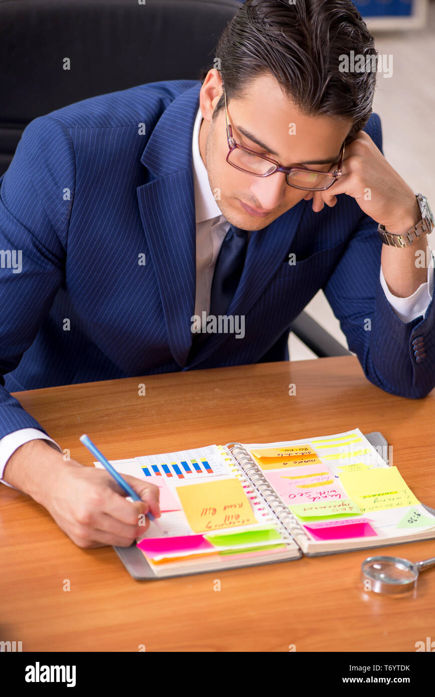 Die jungen gutaussehenden Mitarbeiter Planung seine Tätigkeit Stockfoto