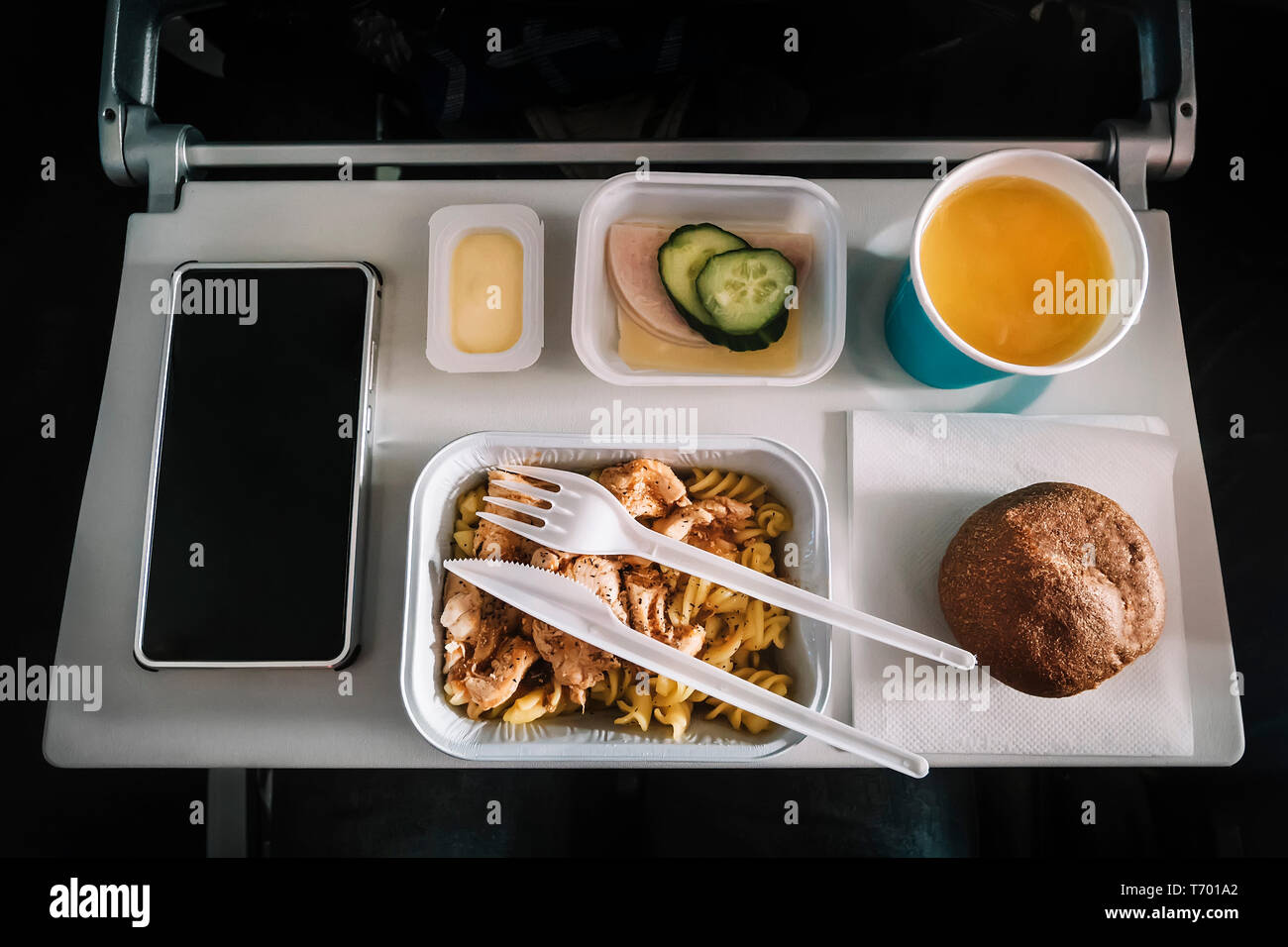 Mahlzeit per Flugzeug service Fach für Economy Class, Fleisch mit Nudeln,  Gewürze Obst, Salat, Gurke, ein Glas Saft und Butter. Selektive  konzentrieren Stockfotografie - Alamy