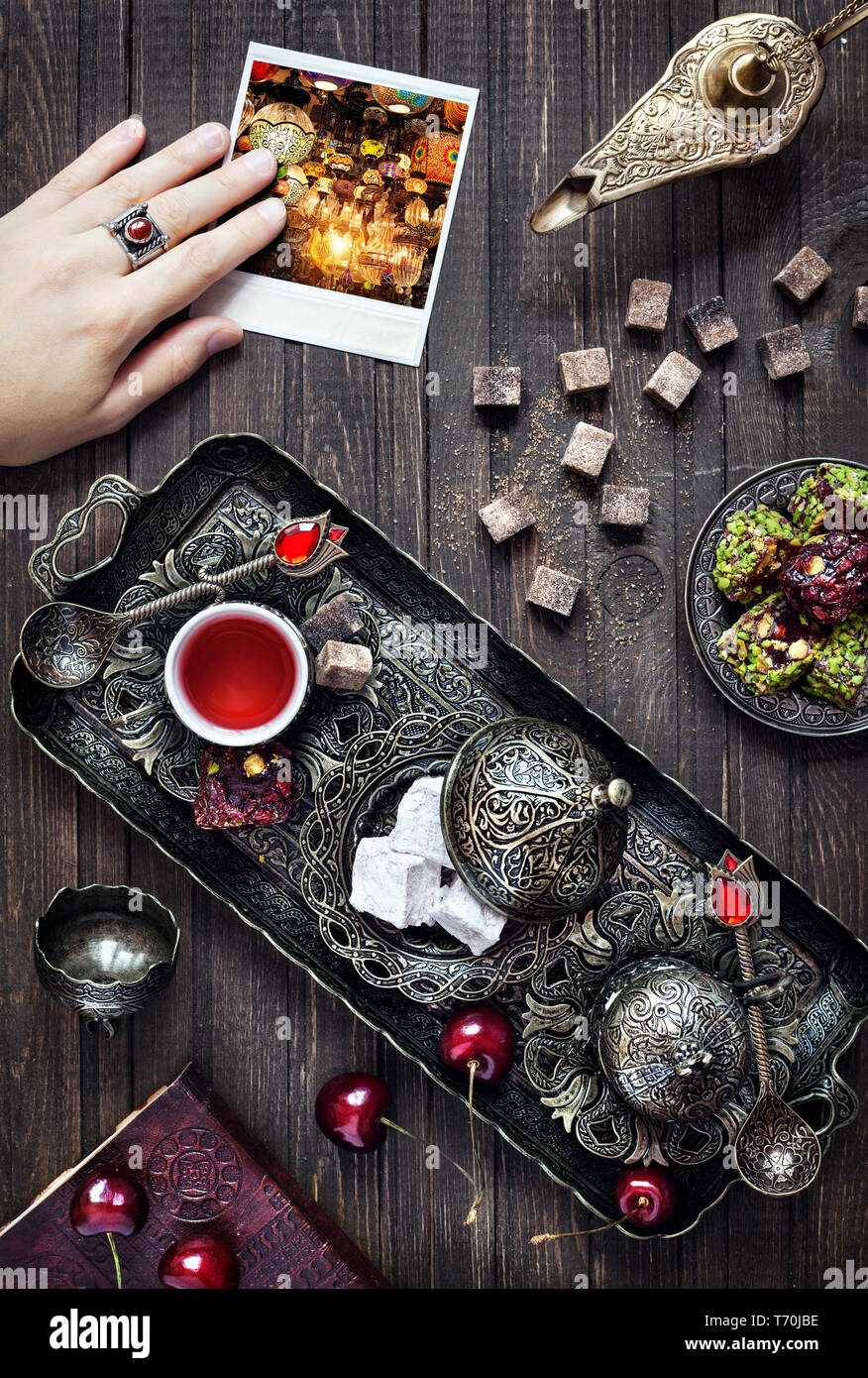 Türkische Köstlichkeiten rahat Lokum, Tee in vintage Teller, Aladins Wunderlampe und Frau Hand durchlöcherte Foto mit leuchtenden Laternen in Istanbul Stockfoto