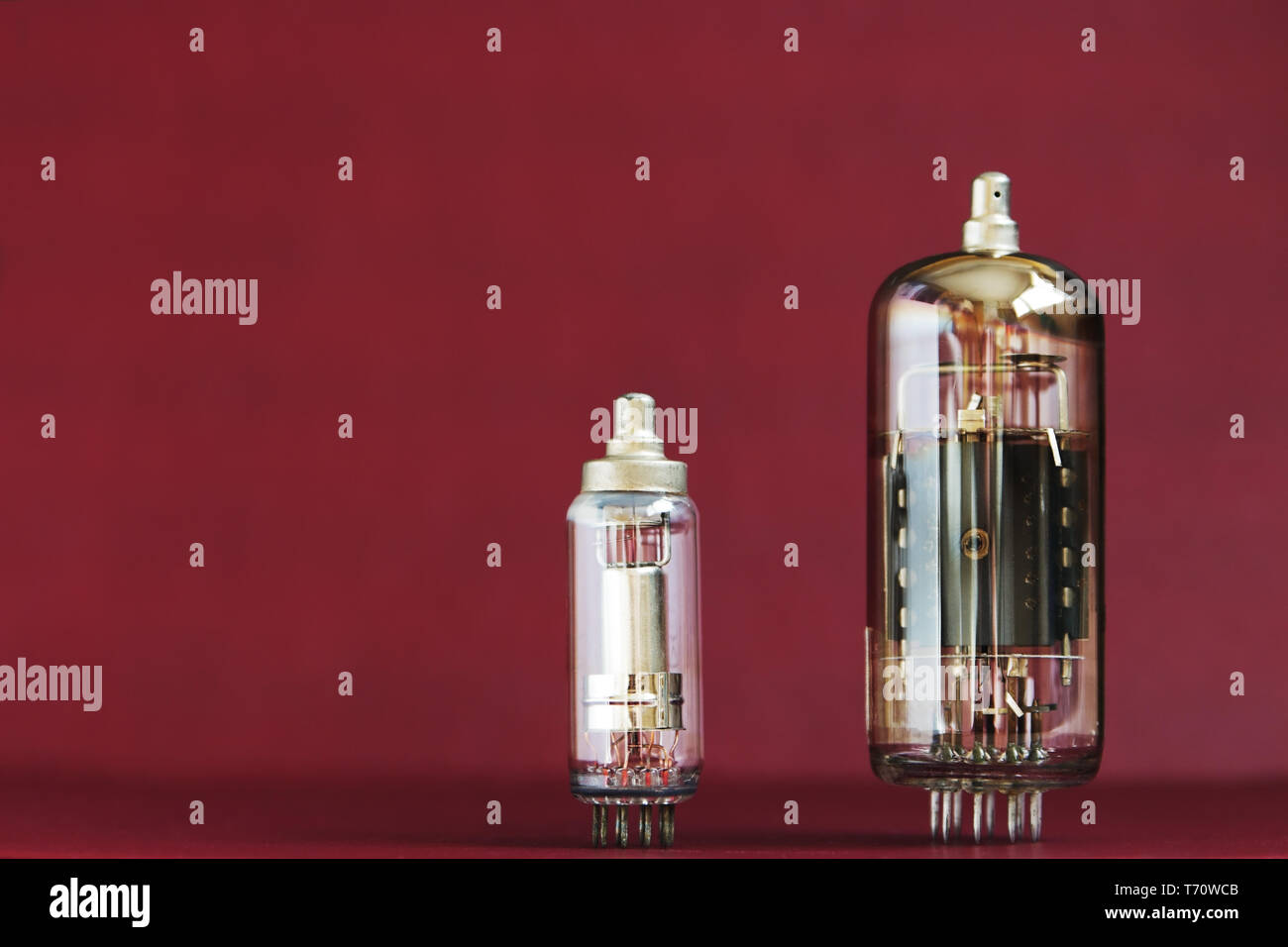 Zwei elektronische Vakuumröhren auf rotem Hintergrund mit dem Text Raum Stockfoto