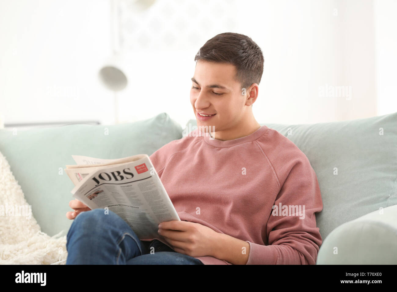 Schöner mann Lesen der Zeitung auf dem Sofa zu Hause Stockfoto
