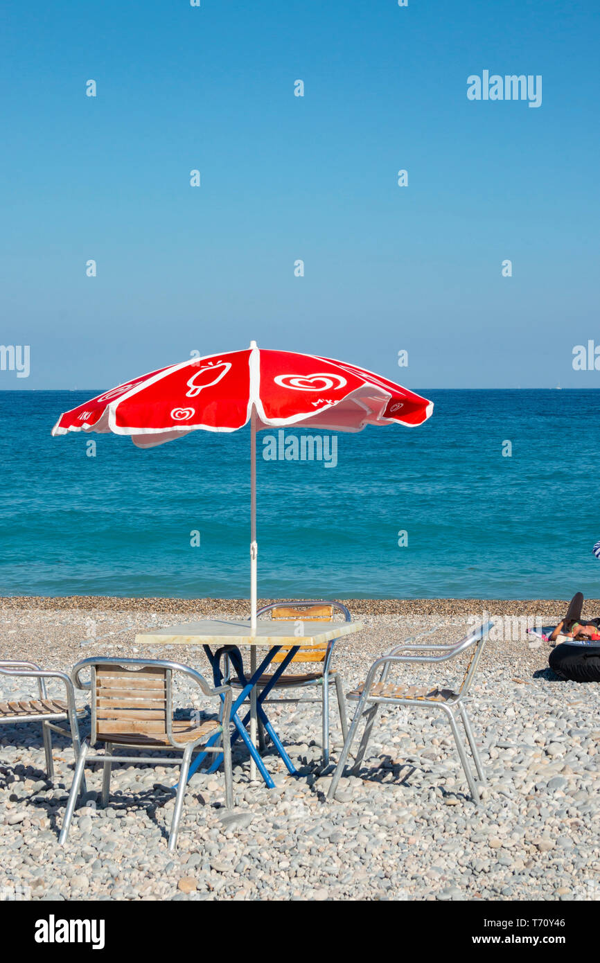 Rote Sonne Schatten Regenschirm auf steinigen Französisch Strand Stockfoto