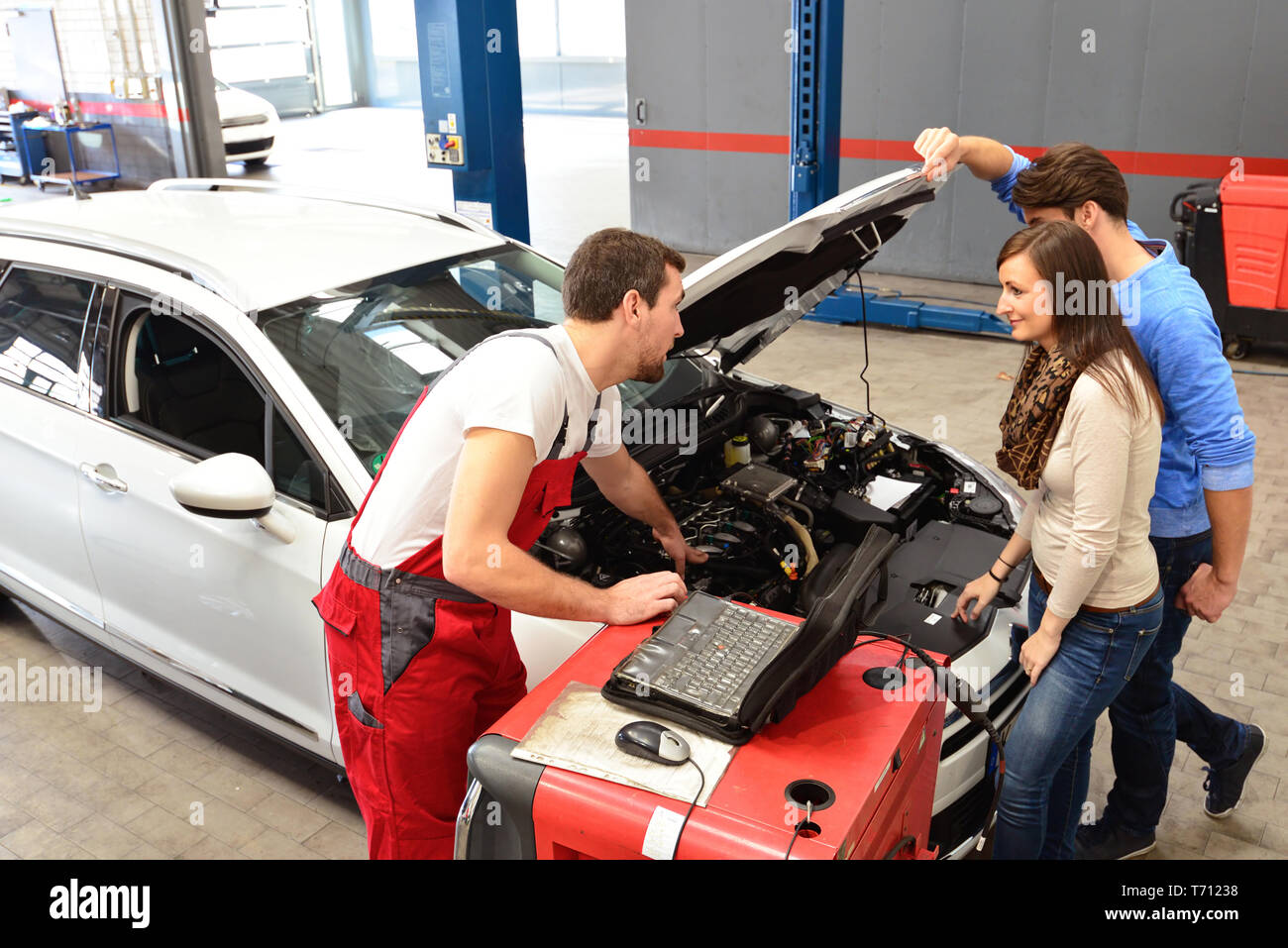 Kundendienst in einer Garage - Mechaniker und die Reparatur eines Fahrzeugs besprechen Stockfoto