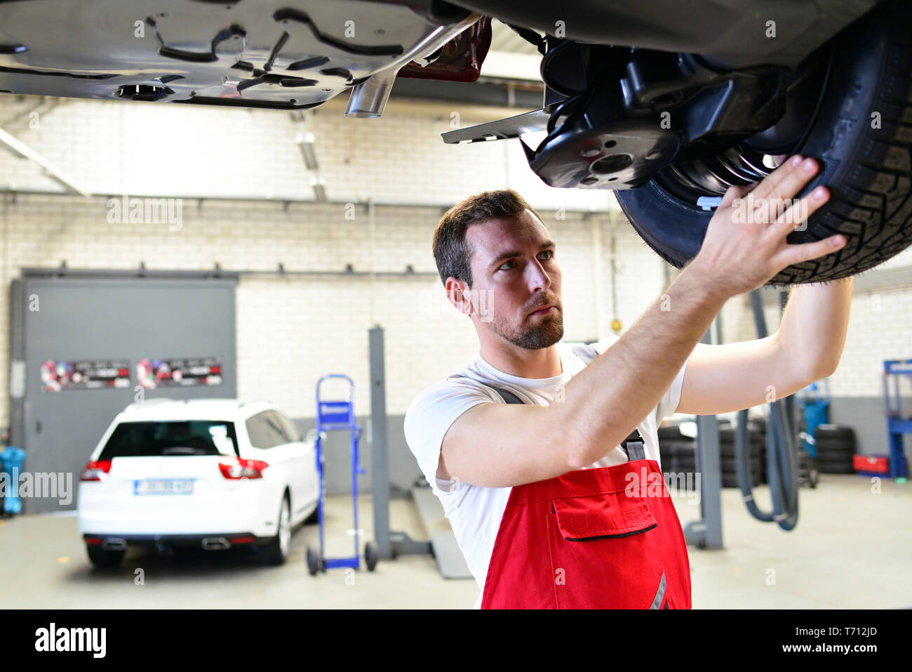 Professionelle Automechaniker arbeitet in einer Werkstatt und Reparaturen Fahrzeuge - die Technologie, die Bremsen und die Reifen prüfen Stockfoto