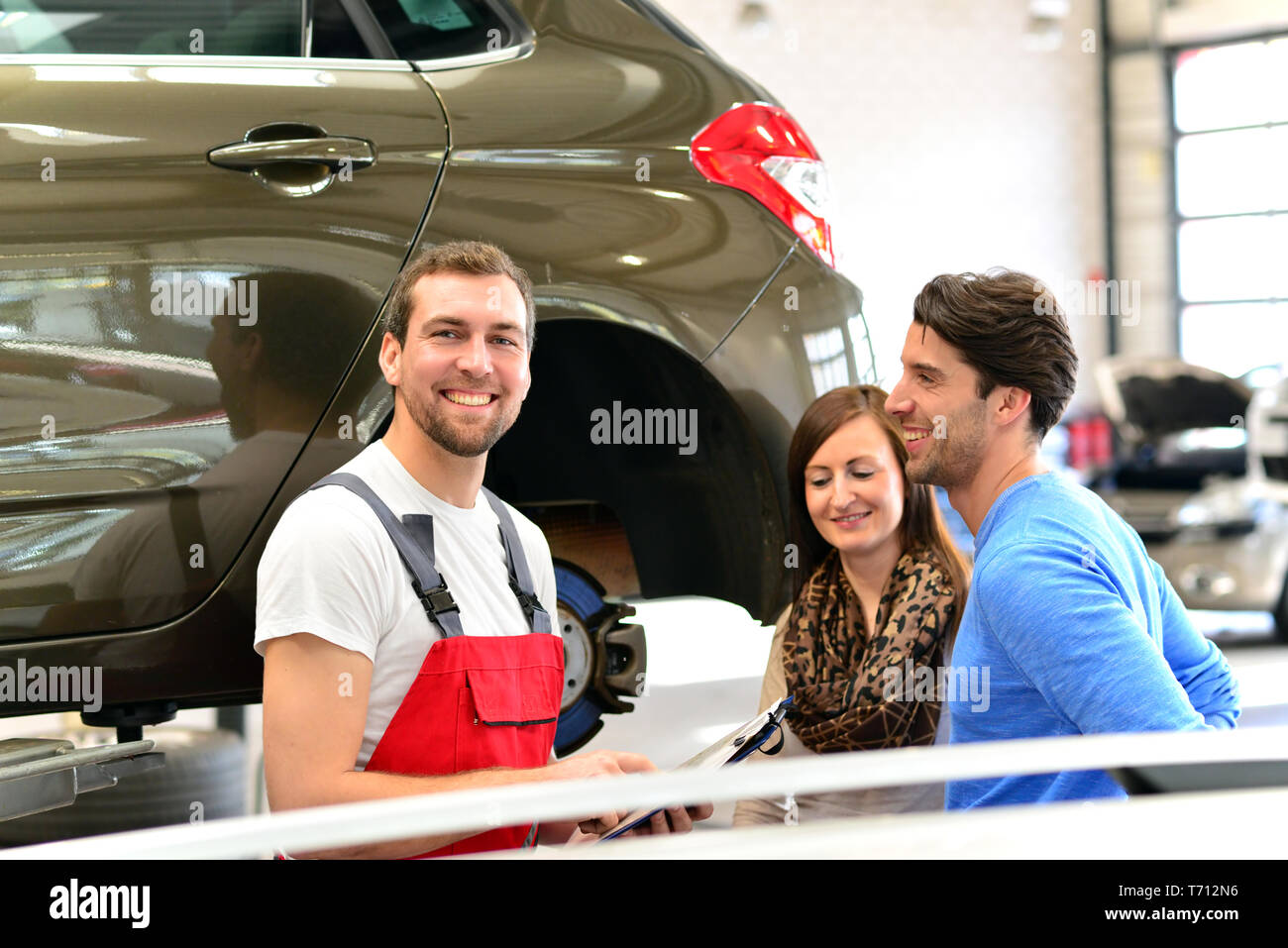 Kundendienst in einer Garage - Mechaniker und die Reparatur eines Fahrzeugs besprechen Stockfoto