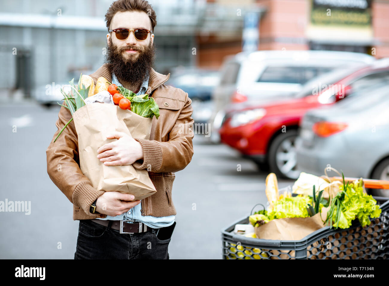 Gerne stilvolle Mann mit Tüten voller Frische und gesunde Lebensmittel im Freien in der Nähe der Supermarkt Stockfoto