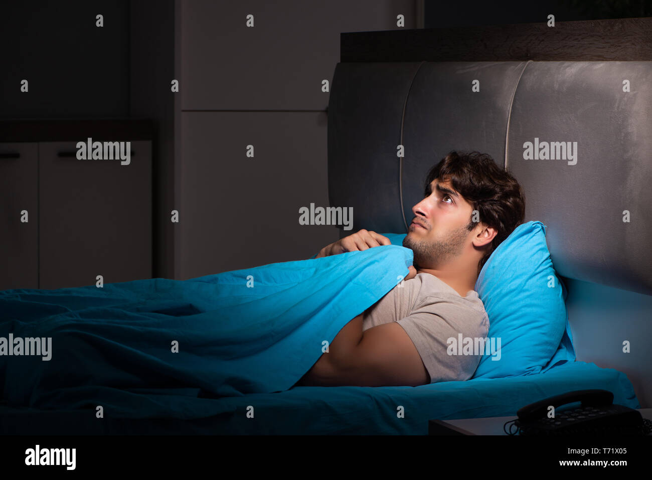 Jungen gutaussehenden Mann leidet unter Schlaflosigkeit im Bett Stockfoto
