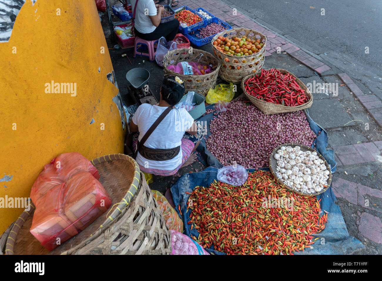 Verkäufer von Gewürzen wie rote Chilischote, rote Zwiebel und Knoblauch sind, verkaufen ihren Handel in einer Ecke des traditionellen Badung Markt Stockfoto