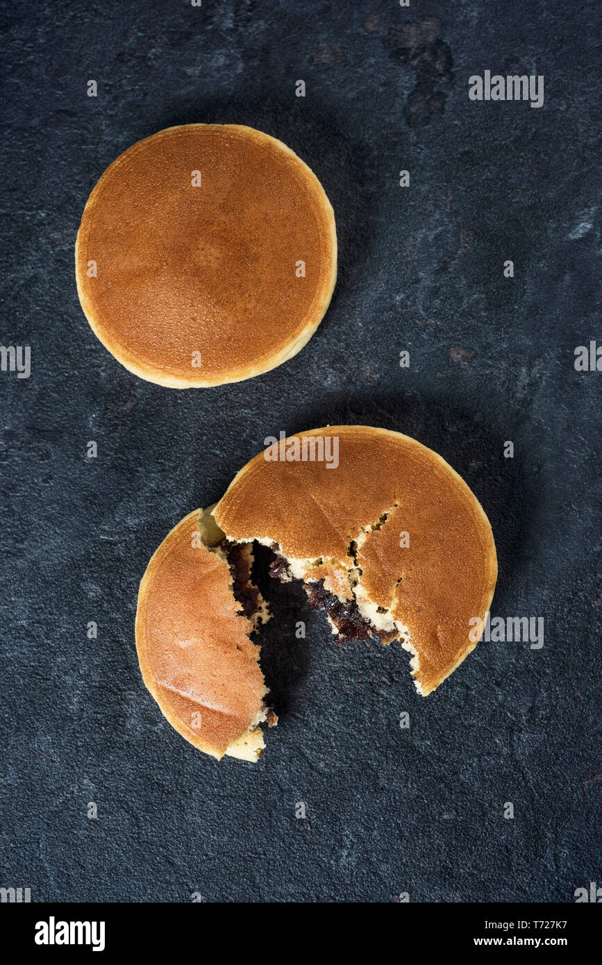 Hohe Betrachtungswinkel von zwei dorayaki, ein Gebäck mit Adzuki bean Paste typisch für Japan gefüllt, auf einer eleganten schwarzen Stein Oberfläche Stockfoto