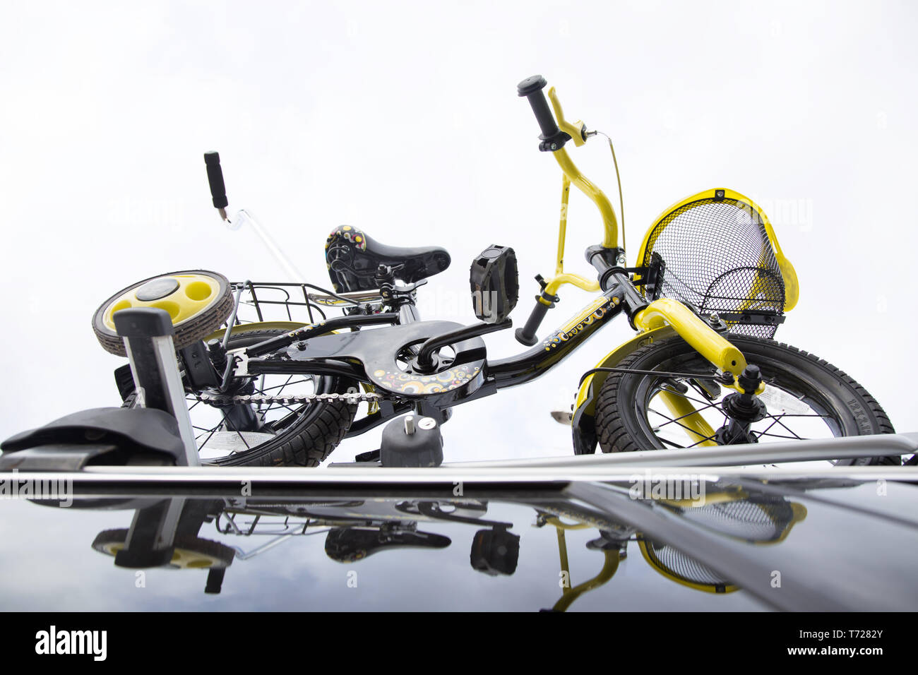 Fahrrad Transport - Kinder Fahrrad auf dem Dach eines Autos gegen den Himmel in eine spezielle Halterung für den Radsport. Die Entscheidung große Lasten zu transportieren Stockfoto