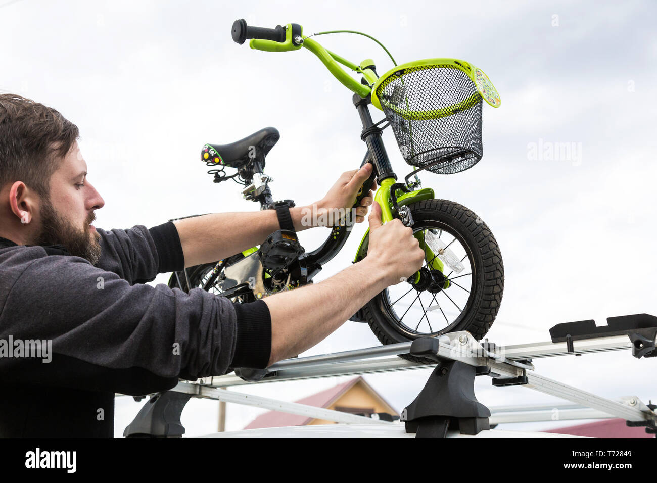 Fahrrad Transport - ein Mann befestigt und installiert ein Fahrrad auf dem  Dach eines Autos in einer speziellen für die Fahrradmitnahme. Die  Entscheidung Stockfotografie - Alamy